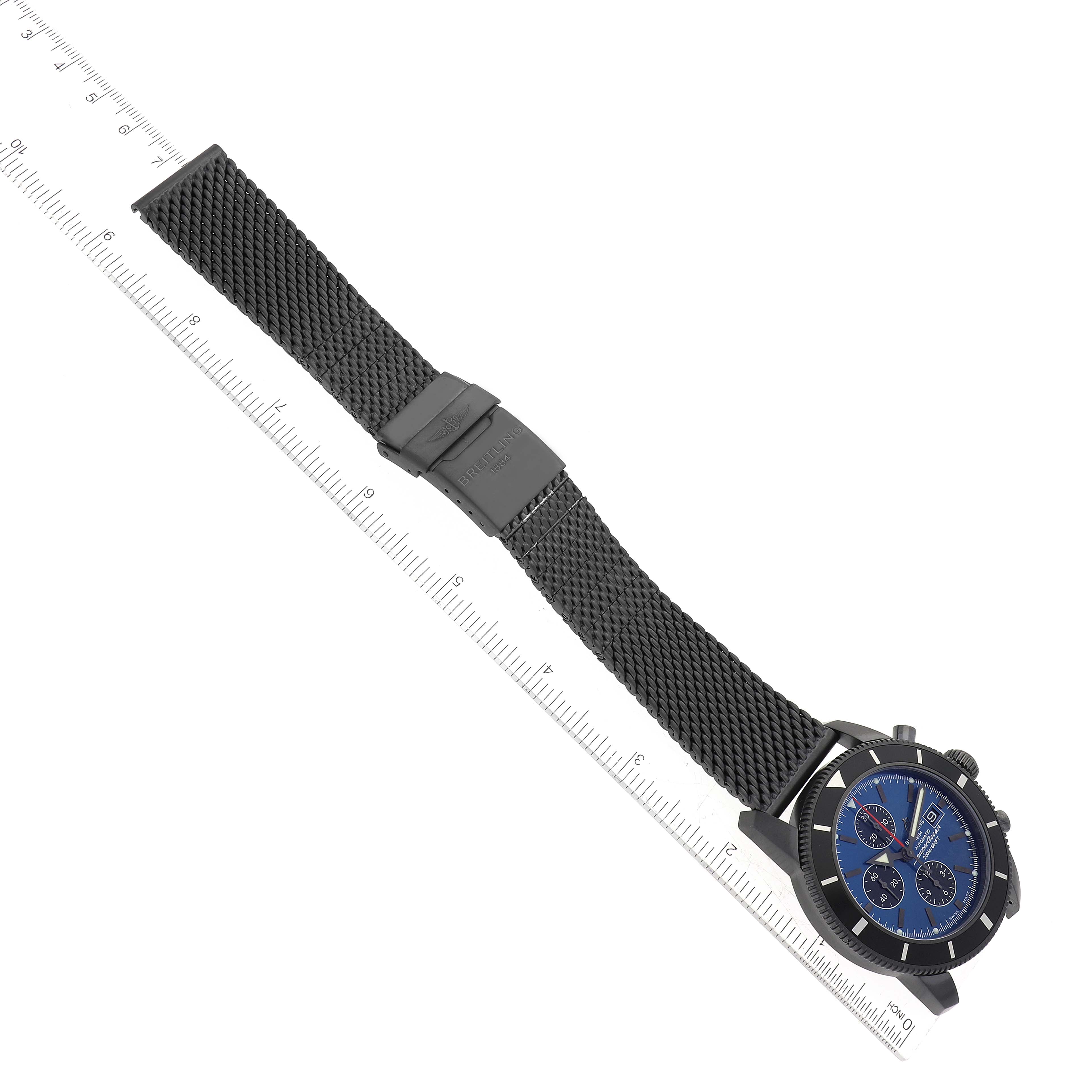 The Breitling Limited Series watch is shown from an overhead angle, highlighting the watch face, mesh strap, and clasp.