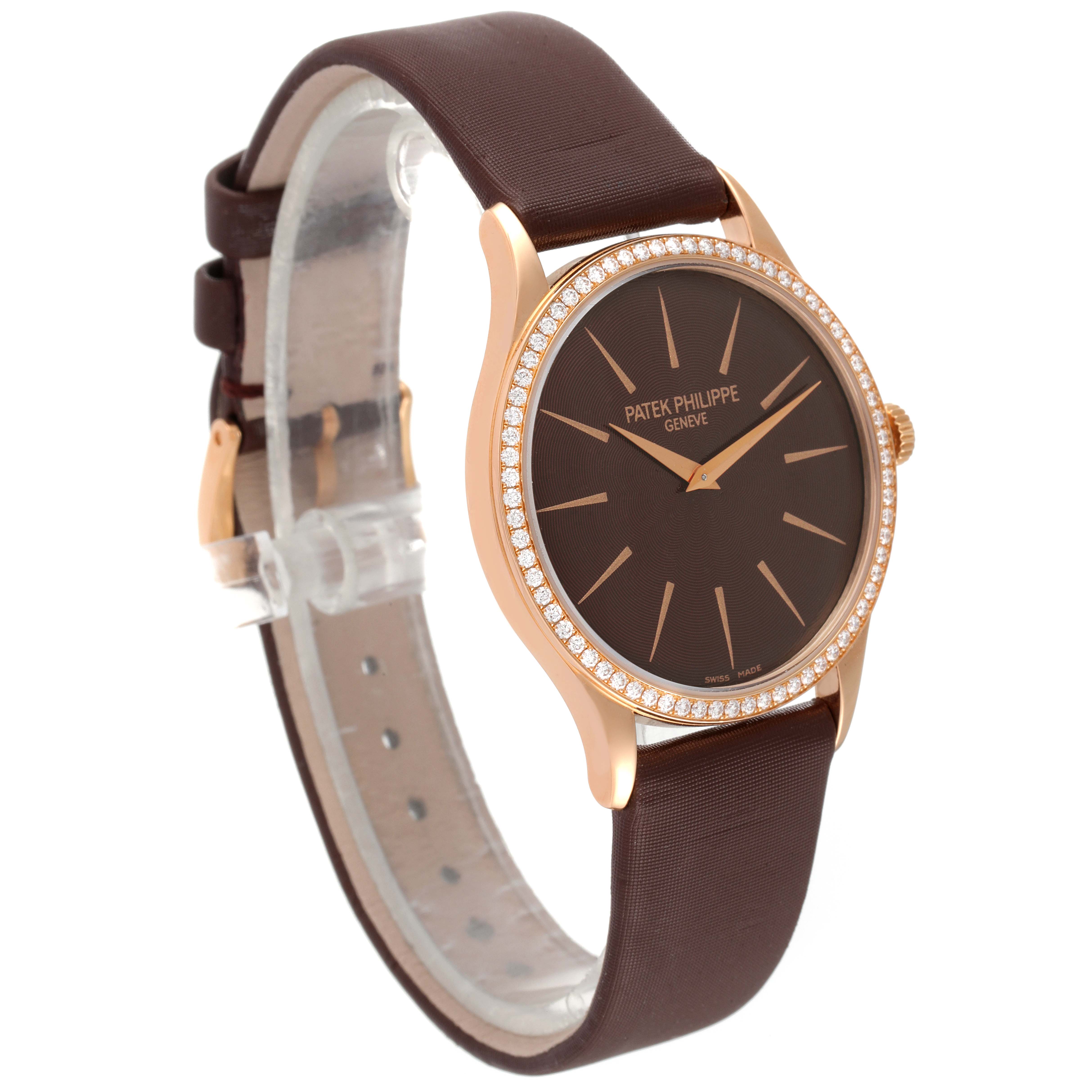 The Patek Philippe Calatrava 4897R-001 Women's Rose Gold Brown Dial 4897R-001 Women's Rose Gold Brown Dial watch is shown at a front-side angle, displaying its brown dial, gold hands, diamond-set bezel, and brown strap.
