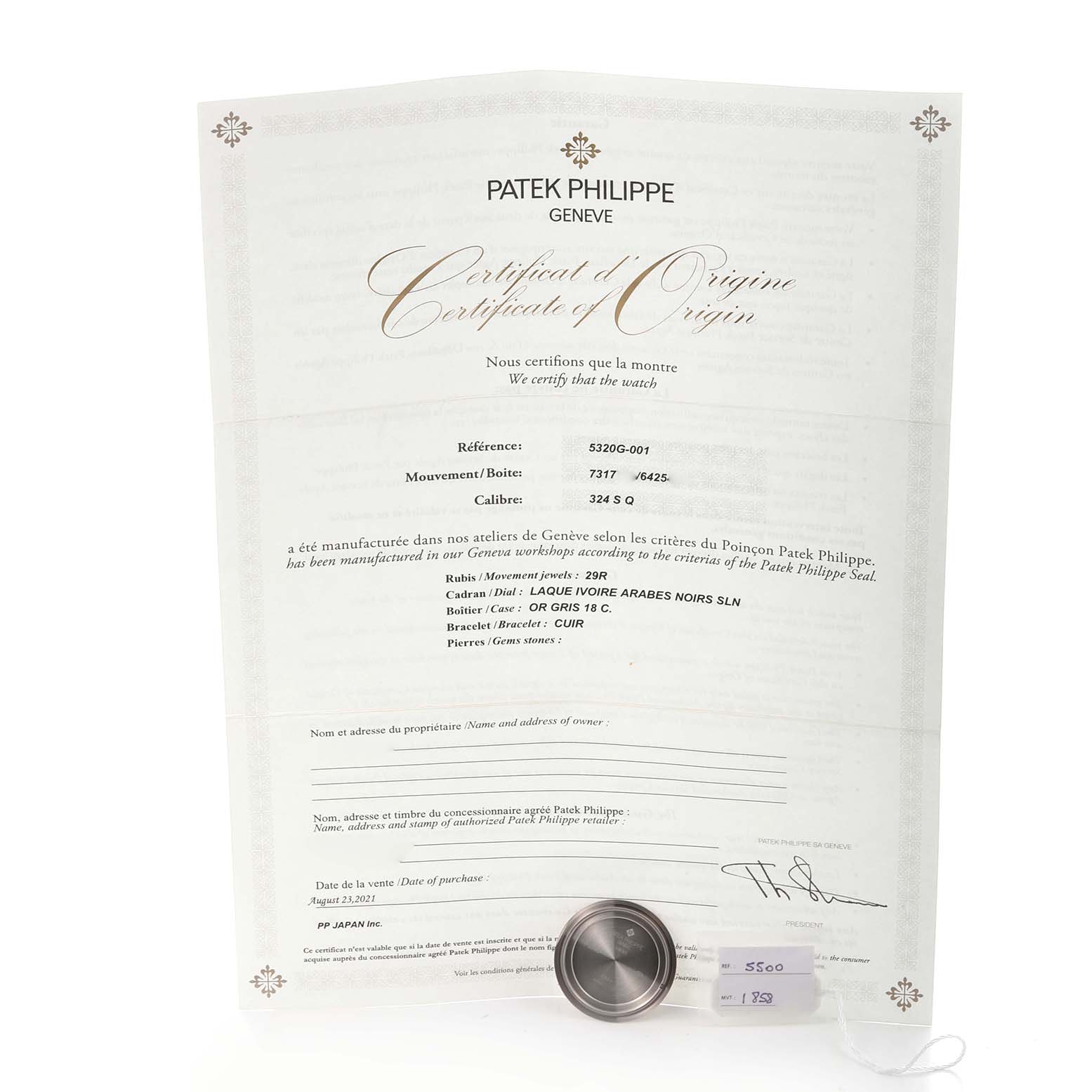 The image shows a Patek Philippe Complications 5320G-001 Men's White Gold White Dial 5320G-001 Men's White Gold White Dial model certificate and a watch accessory, viewed from a top angle.