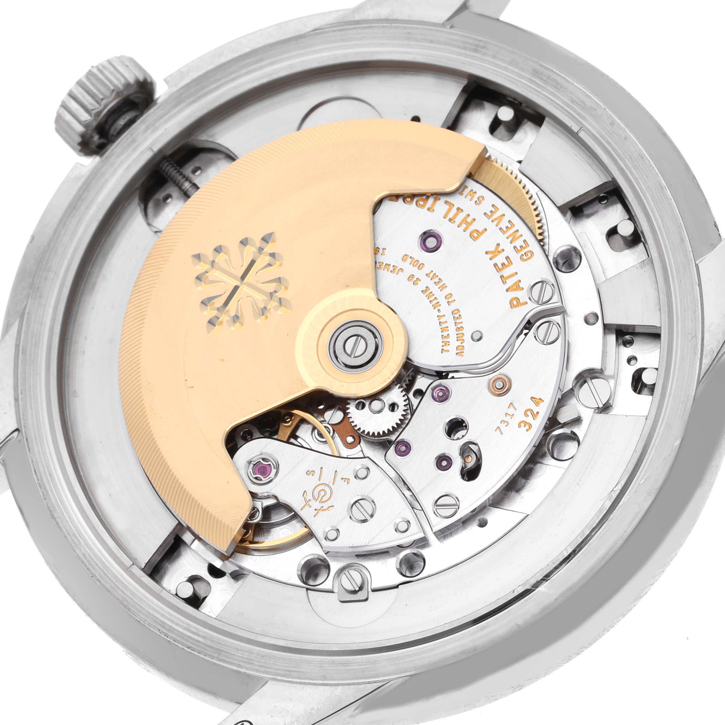 The image shows the movement of a Patek Philippe Complications 5320G-001 Men's White Gold White Dial 5320G-001 Men's White Gold White Dial watch from a rear angle, highlighting gears and the rotor.