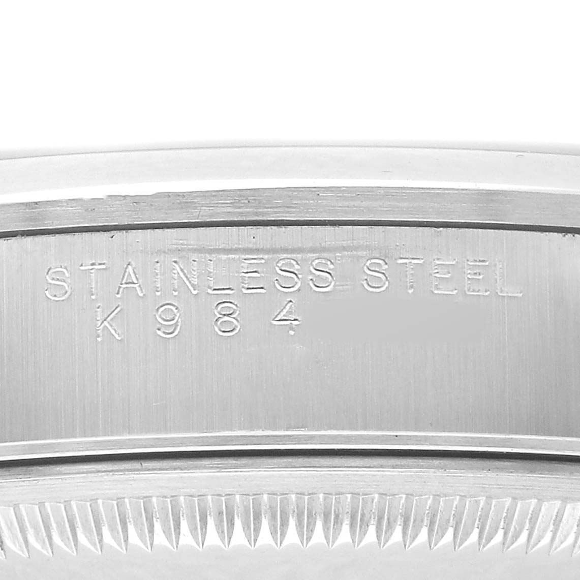 The image shows an engraving on the case side of a Rolex Date 15200 Men's Stainless Steel Blue Dial model, highlighting "STAINLESS STEEL" and serial number details.