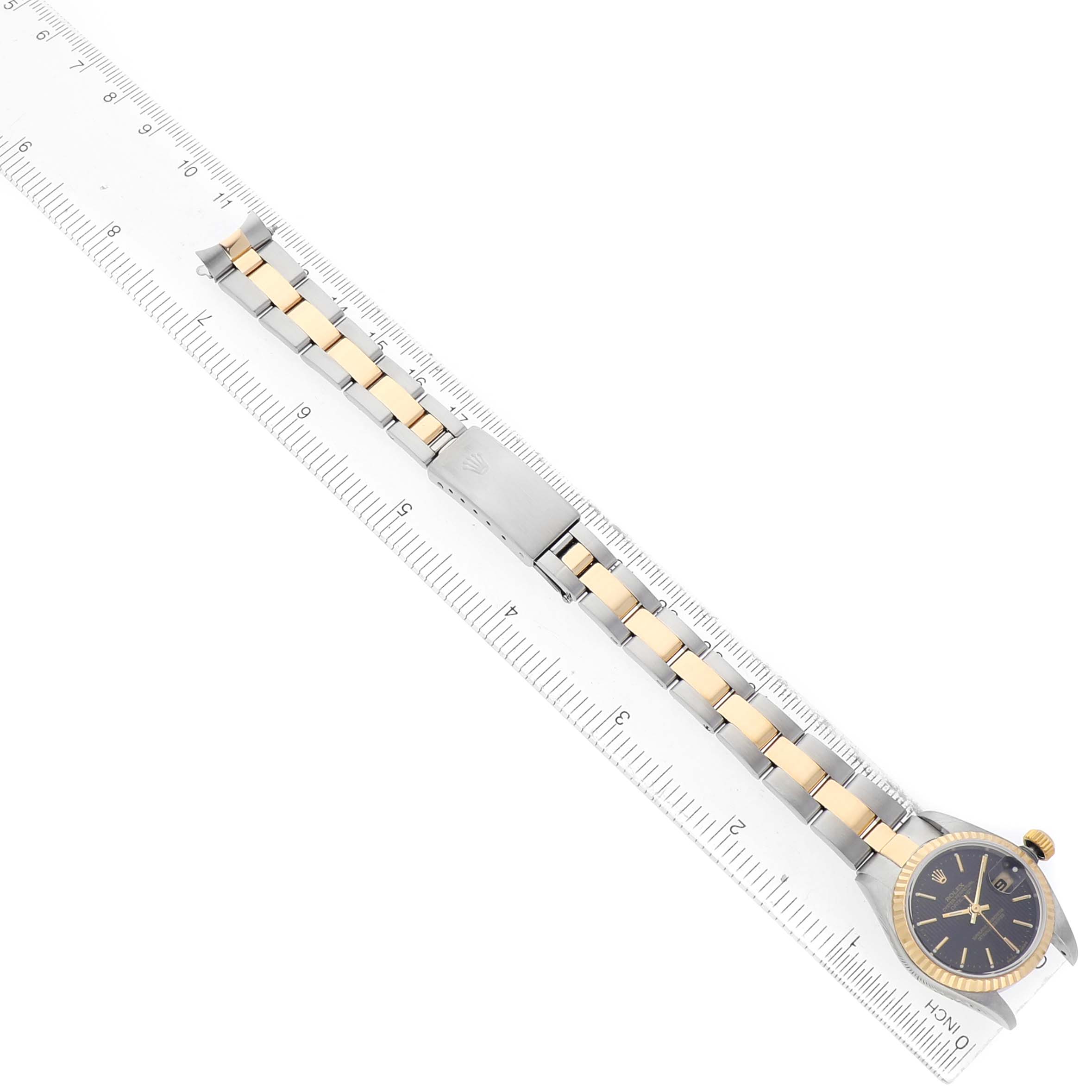 The image shows a Rolex Datejust 79173 Women's Steel and Gold (two tone) Black Dial watch from a top view, focusing on its two-tone bracelet and black dial alongside a ruler.