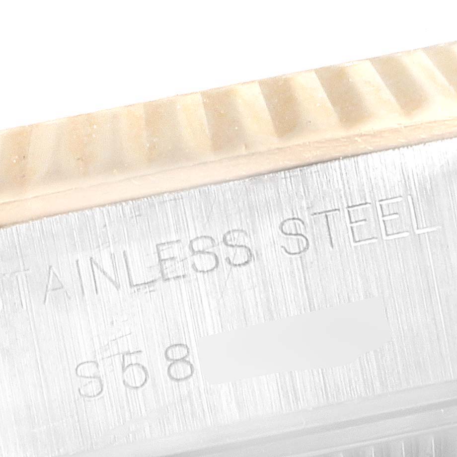 This image shows a close-up angle of the side of a Rolex Datejust 69173 Women's Steel and Gold (two tone) Blue Dial 69173 Women's Steel and Gold (two tone) Blue Dial watch, highlighting the fluted bezel and engraved stainless steel text.