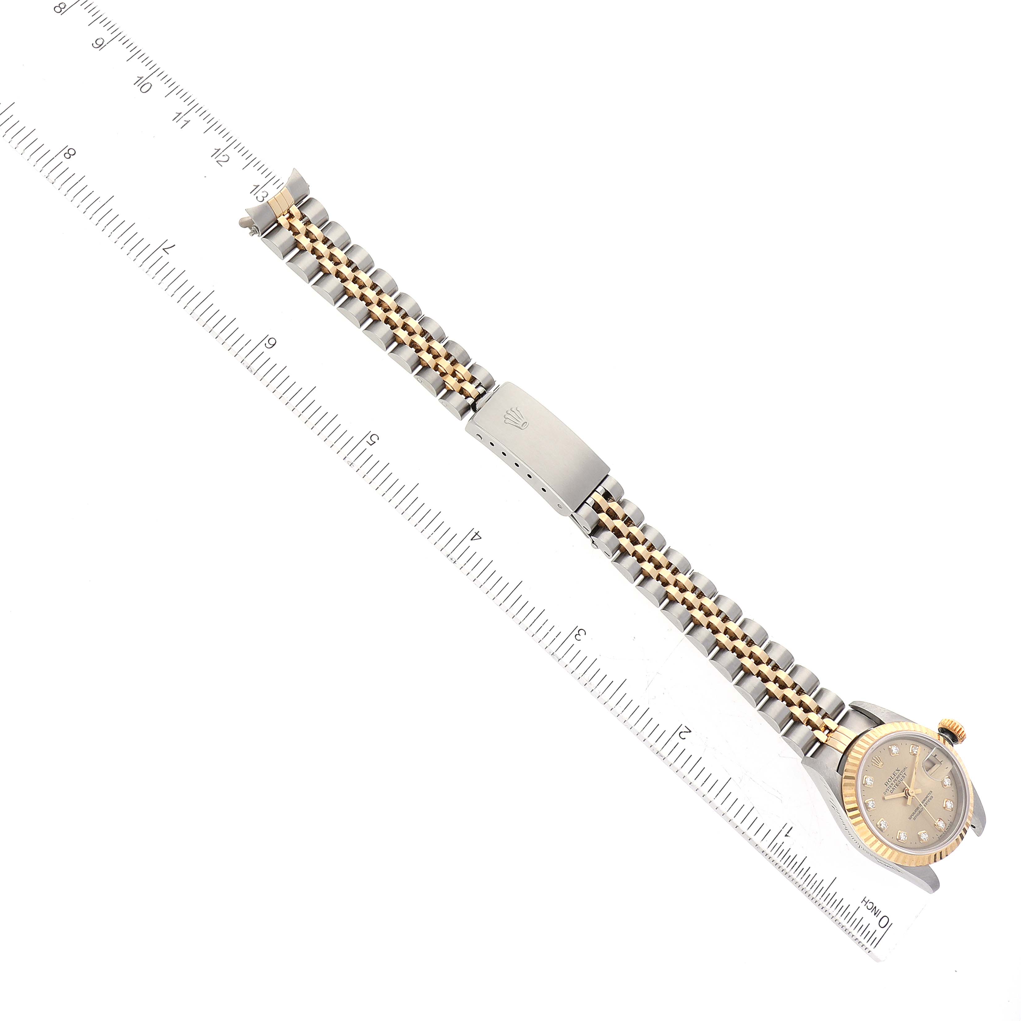 The Rolex Datejust 69173 Women's Steel and Gold (two tone) Champagne Dial 69173 Women's Steel and Gold (two tone) Champagne Dial watch is displayed flat with the face partially visible and the bracelet aligned next to a ruler.