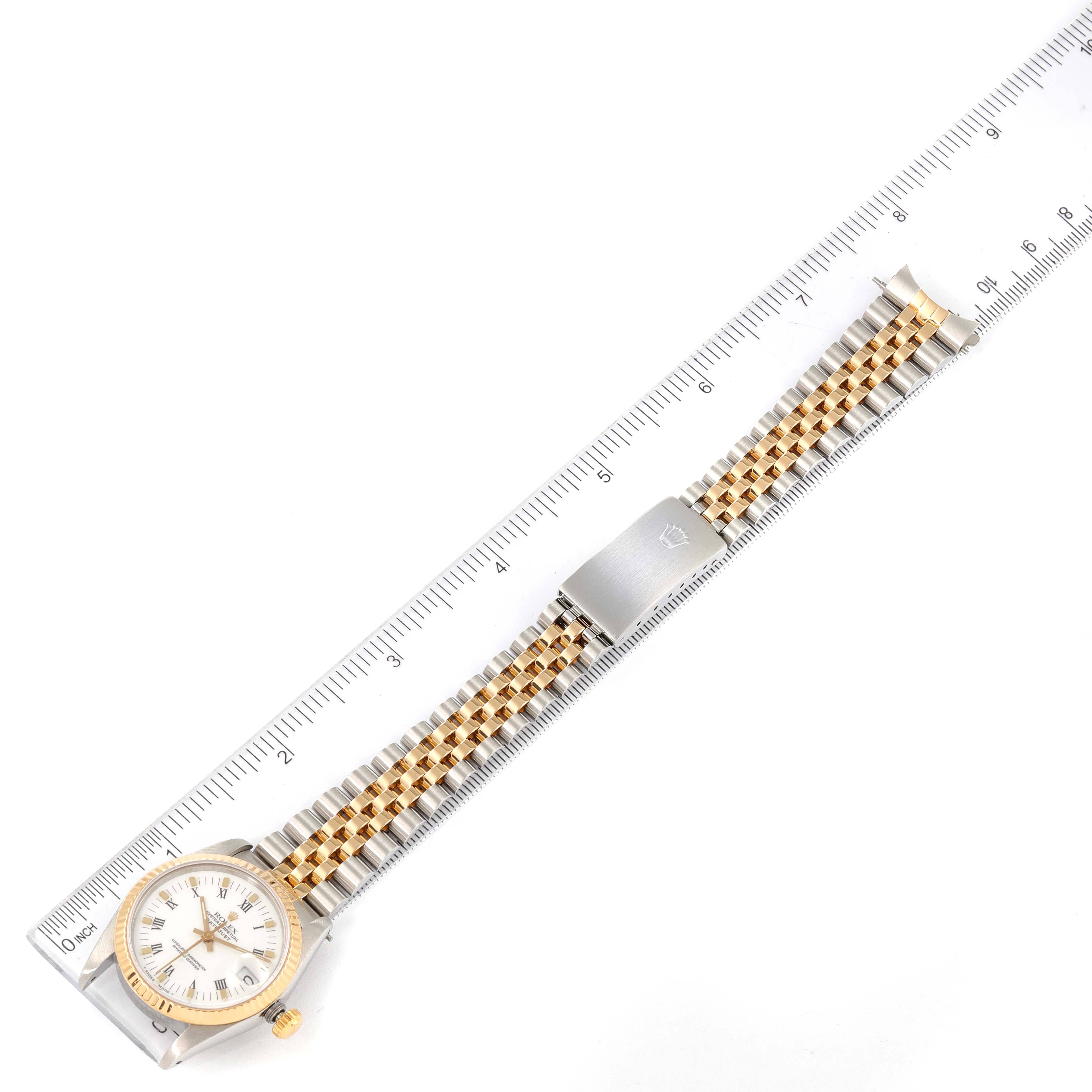 This image shows a top view of a Rolex Mid-Size 68273 Women
s Steel and Gold (two tone) White Dial 68273 Women
s Steel and Gold (two tone) White Dial watch with a two-tone metal bracelet, laid alongside a ruler for scale.