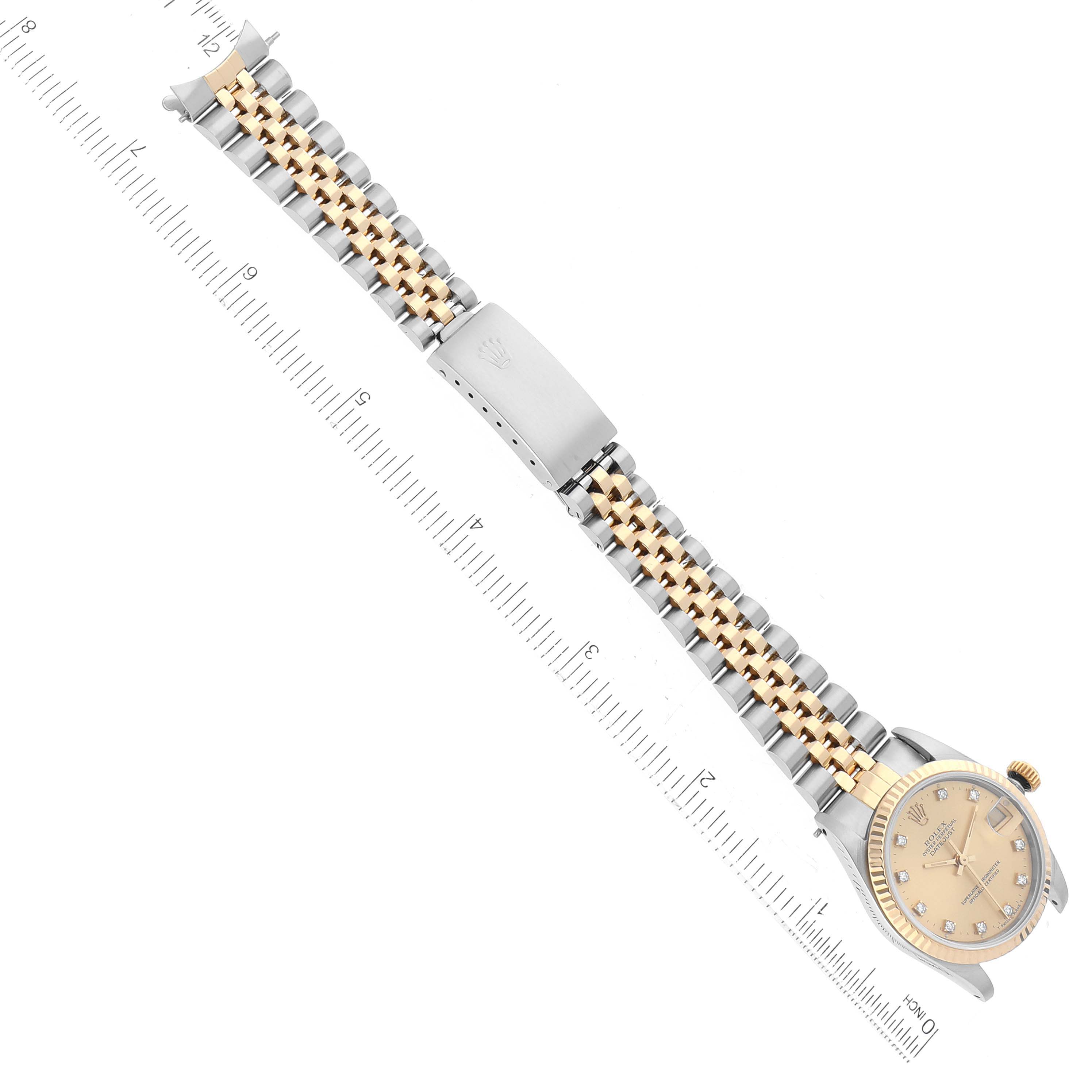 This image shows the top view of a Rolex Mid-Size 68273G Women's Steel and Gold (two tone) Champagne Dial 68273G Women's Steel and Gold (two tone) Champagne Dial watch with its face and entire two-tone metal band alongside a ruler.