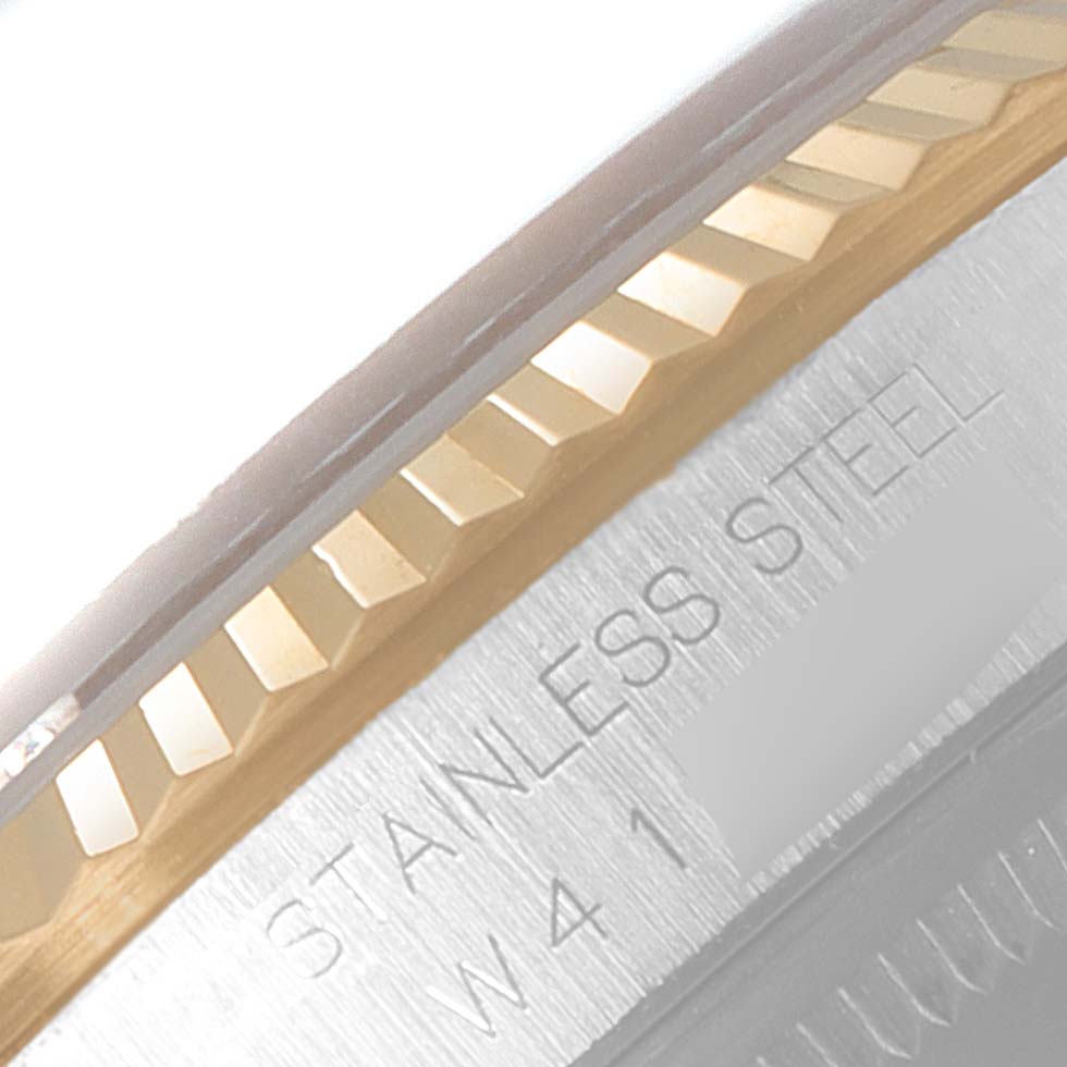 This close-up image of the Rolex Datejust 16233 Men's Steel and Gold (two tone) Champagne Dial 16233 Men's Steel and Gold (two tone) Champagne Dial watch shows the side of the fluted bezel and part of the case engraved with "STAINLESS STEEL."