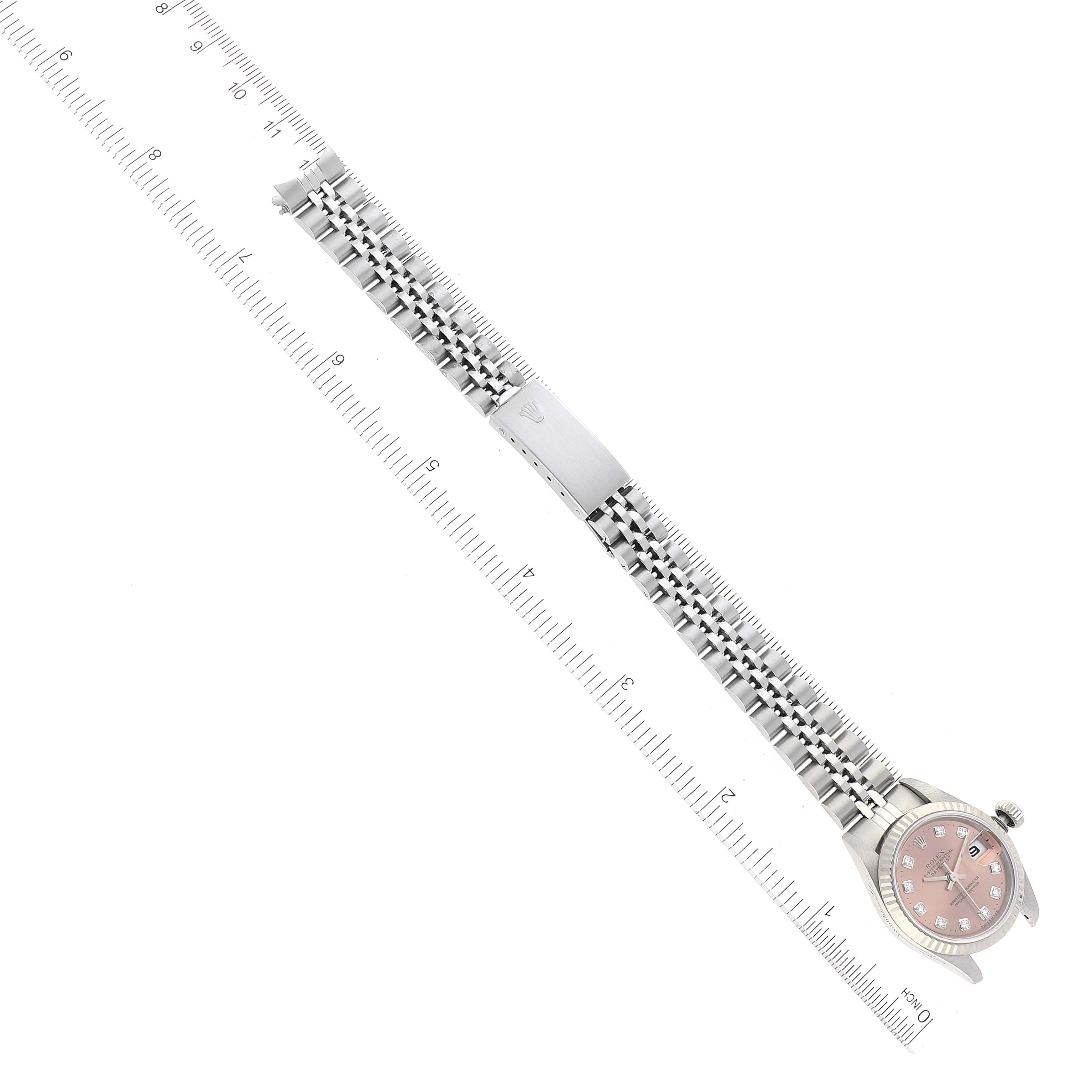 This image shows a Rolex Datejust 79174 Women's Stainless Steel Pink Dial 79174 Women's Stainless Steel Pink Dial watch laid flat next to a ruler, displaying its face, bracelet, and clasp.