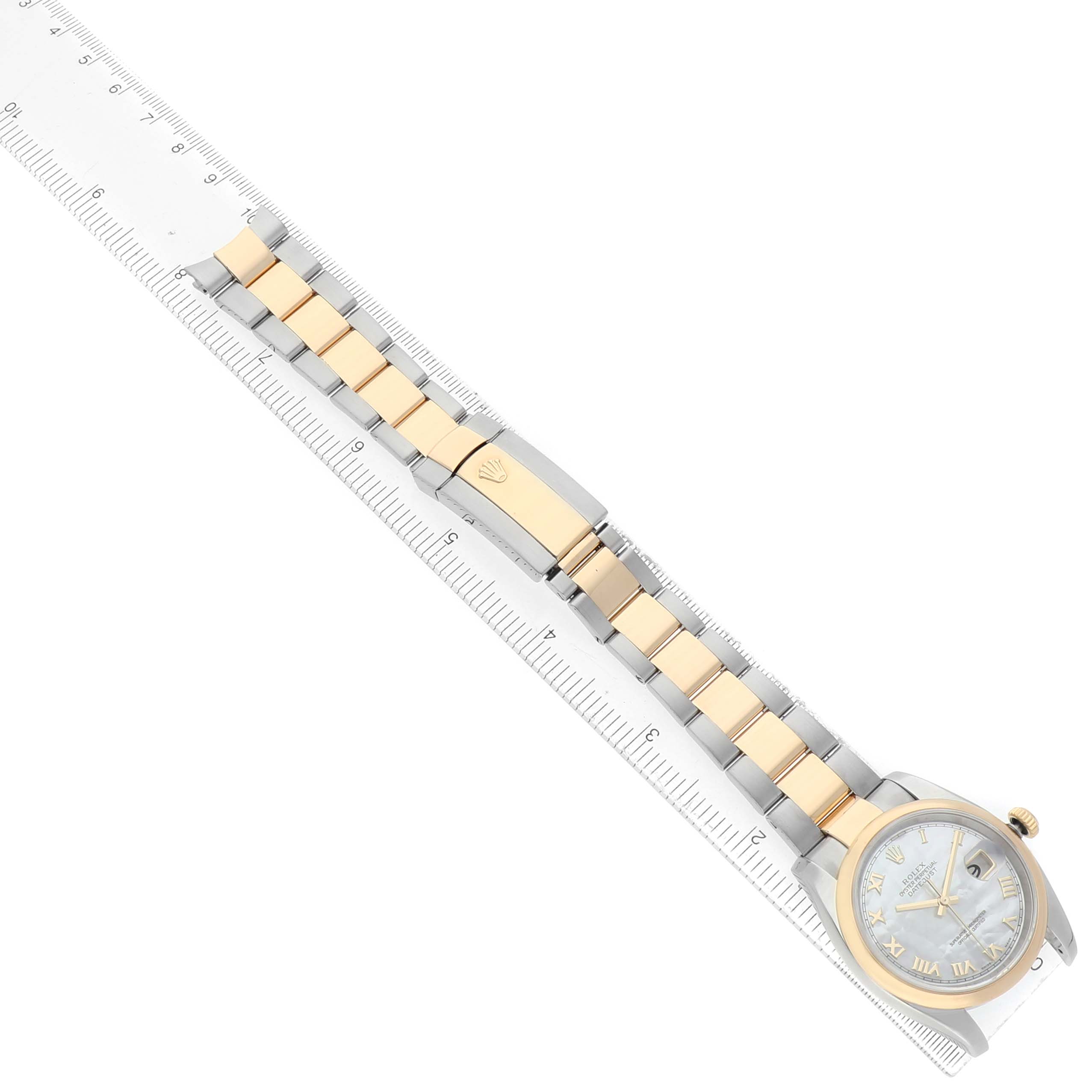 The Rolex Datejust 116203 Men's Steel and Gold (two tone) Mother of Pearl Dial watch is shown from a top-down angle, displaying the full bracelet and partial dial alongside a ruler.