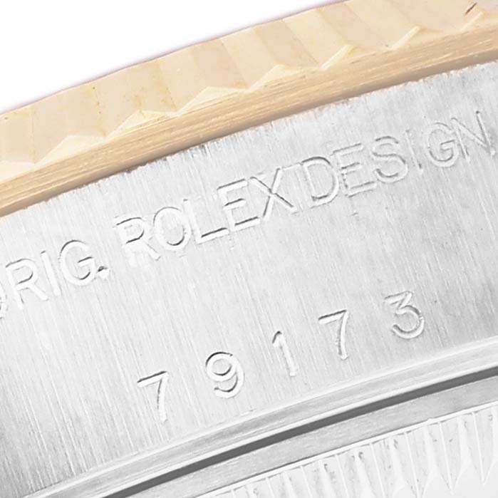 The image shows the side engraving and fluted bezel of a Rolex Datejust ROLEX DATEJUST STEEL YELLOW GOLD SILVER ROMAN DIAL LADIES WATCH 79173 Women's Steel and Gold (two tone) Silver Dial watch.