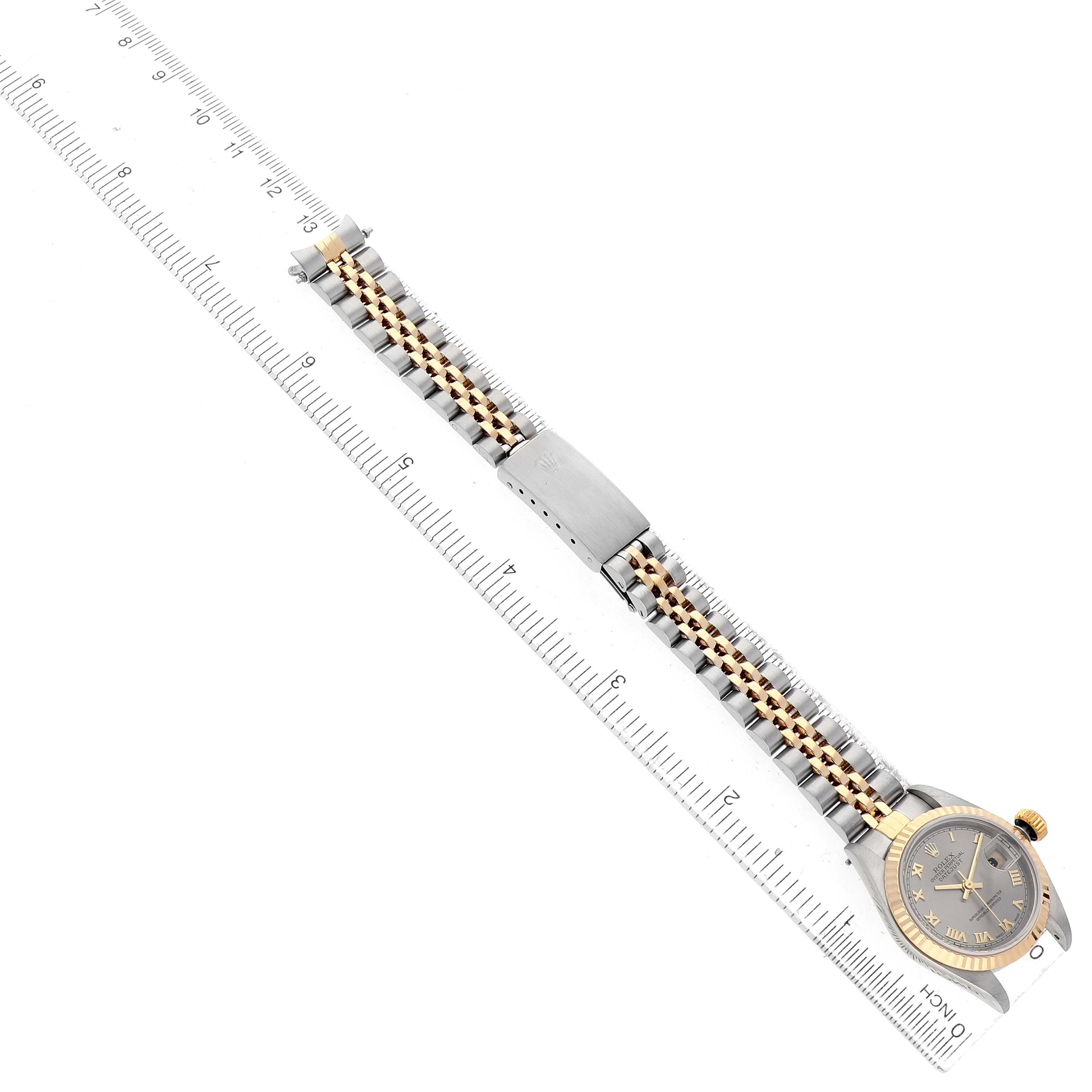 The Rolex Datejust 79173 Women's Steel and Gold (two tone) Silver Dial watch is shown from an overhead view, displaying its two-tone bracelet, clasp, and face beside a ruler.