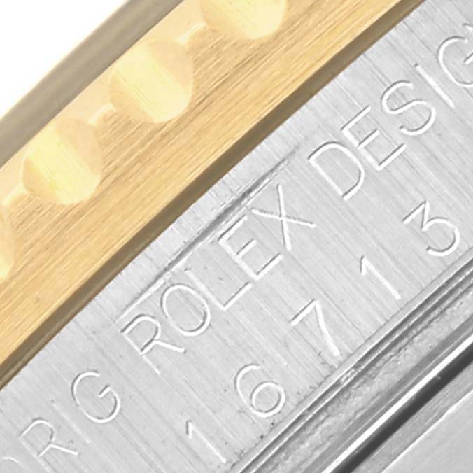 The image shows a close-up of the side engraving and bezel of a Rolex GMT-Master 16713 Men's Steel and Gold (two tone) Black Dial 16713 Men's Steel and Gold (two tone) Black Dial watch.