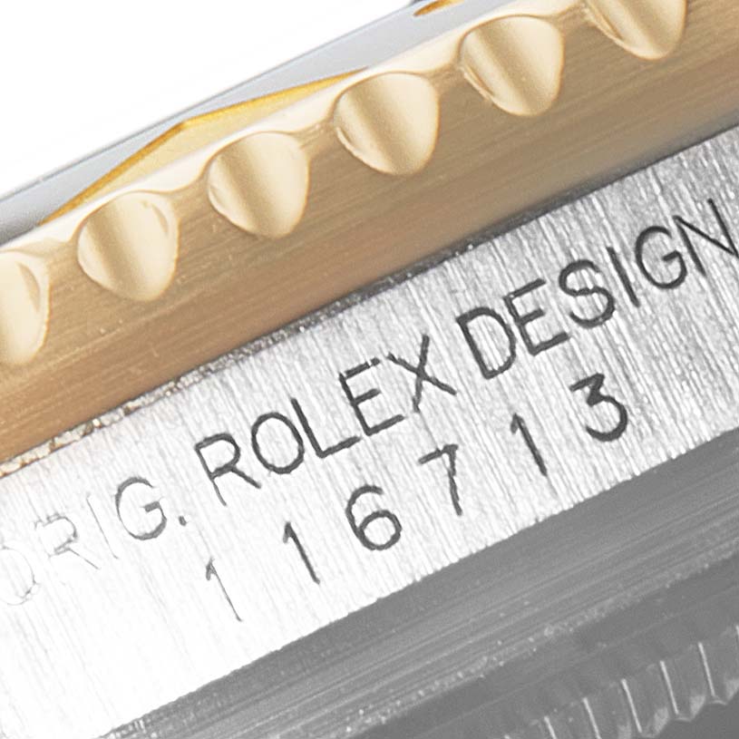 This close-up image shows the edge of a Rolex GMT-Master 116713 Men's Steel and Gold (two tone) Black Dial 116713 Men's Steel and Gold (two tone) Black Dial watch bezel and its model number 116713.