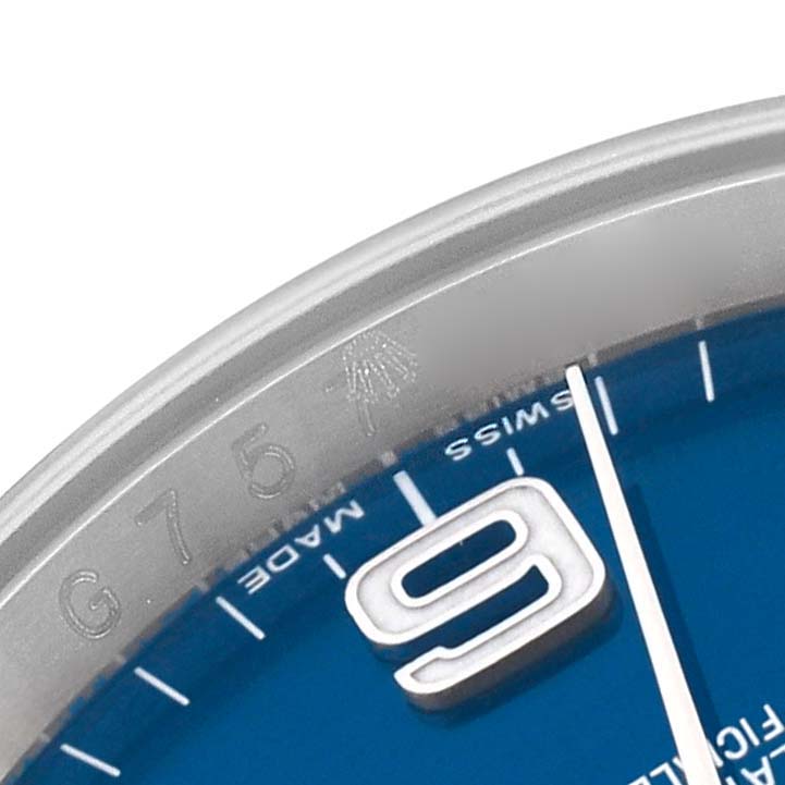 The image shows a close-up of the bezel and part of the blue dial of the Rolex Oyster Perpetual 116000 Men
s Stainless Steel Blue Dial 116000 Men
s Stainless Steel Blue Dial watch, including the number "9" and "SWISS MADE" text.