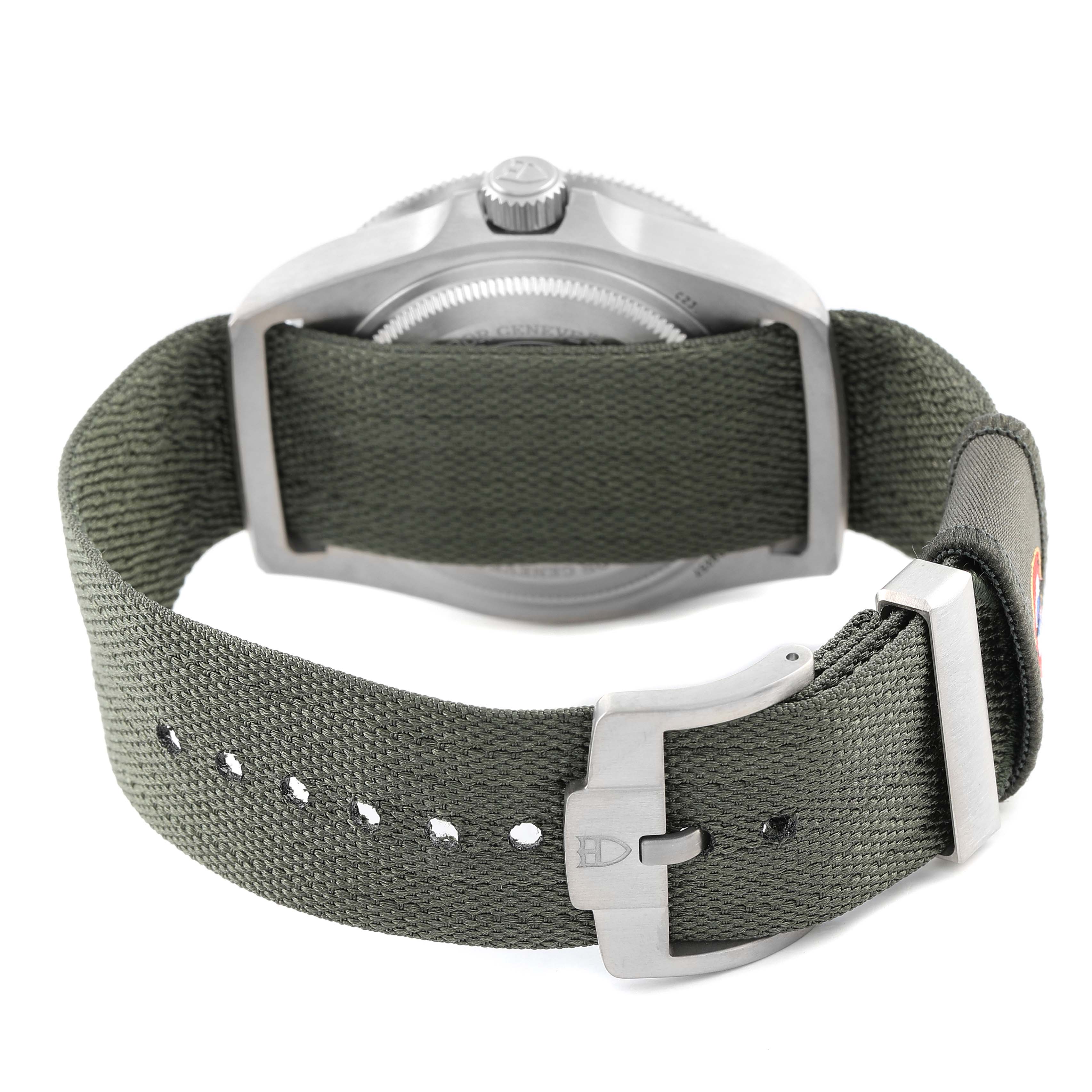 The image shows the back view of a Tudor Pelagos 2542G257 Men's Titanium Black Dial watch, highlighting its green fabric strap and metal buckle.