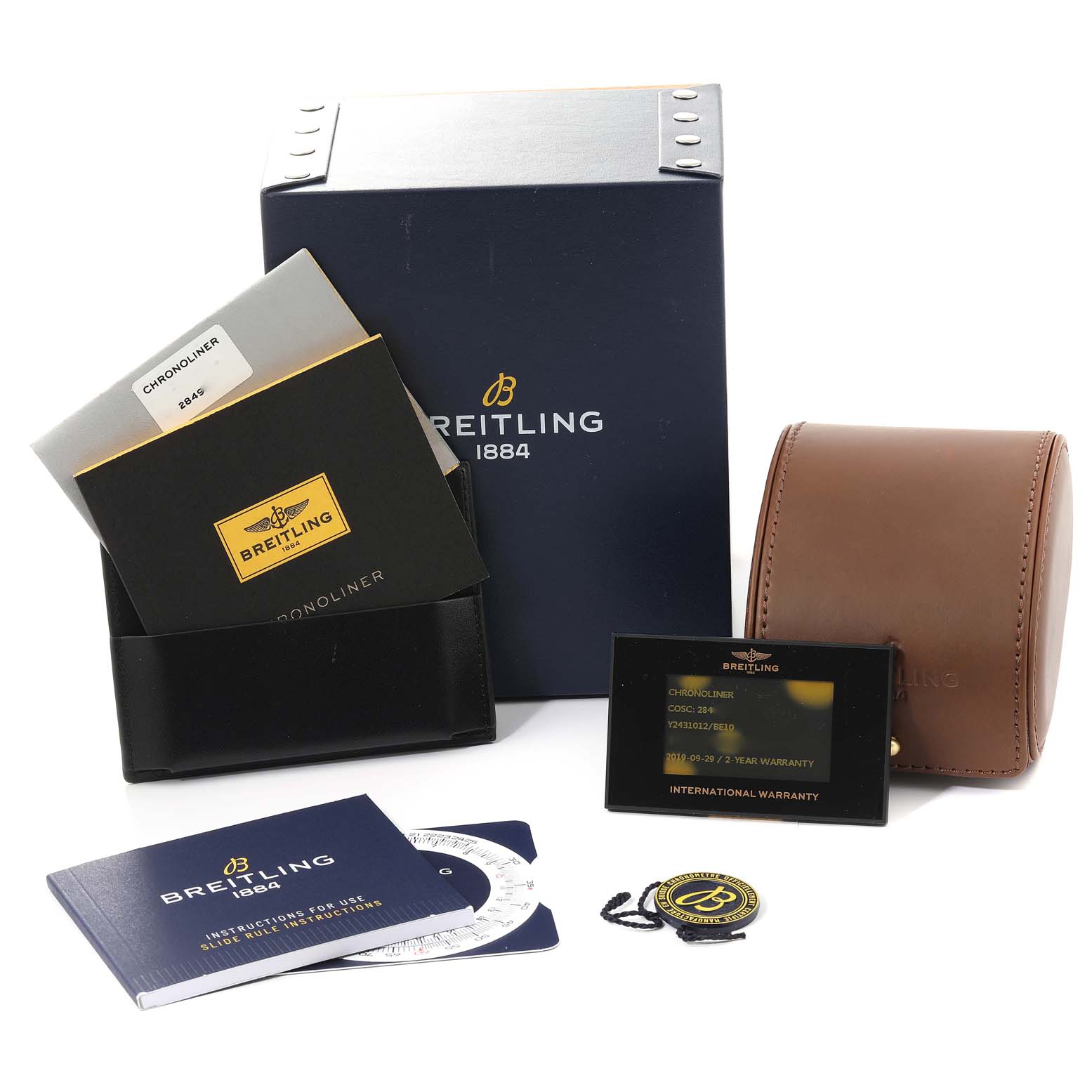The image shows the packaging, warranty card, manuals, and a brown leather case for the Breitling Chronoliner Y2431012/BE10 Men's Stainless Steel Black Dial Y2431012/BE10 Men's Stainless Steel Black Dial watch, all arranged frontally.
