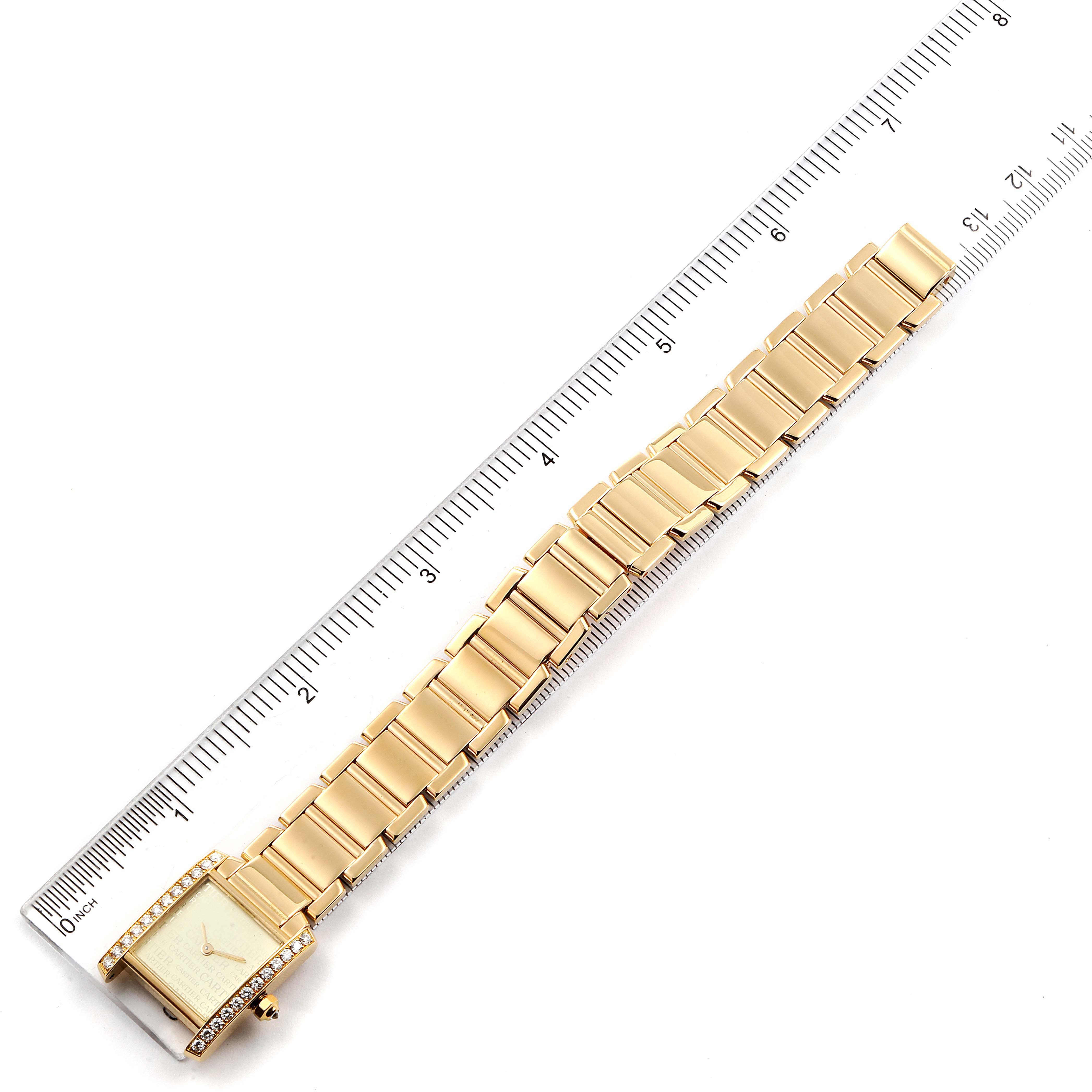 The image shows the top view of a gold Cartier Tank Francaise WE1023R8 Women
s Yellow Gold Silver Dial WE1023R8 Women
s Yellow Gold Silver Dial watch alongside a ruler for size reference.