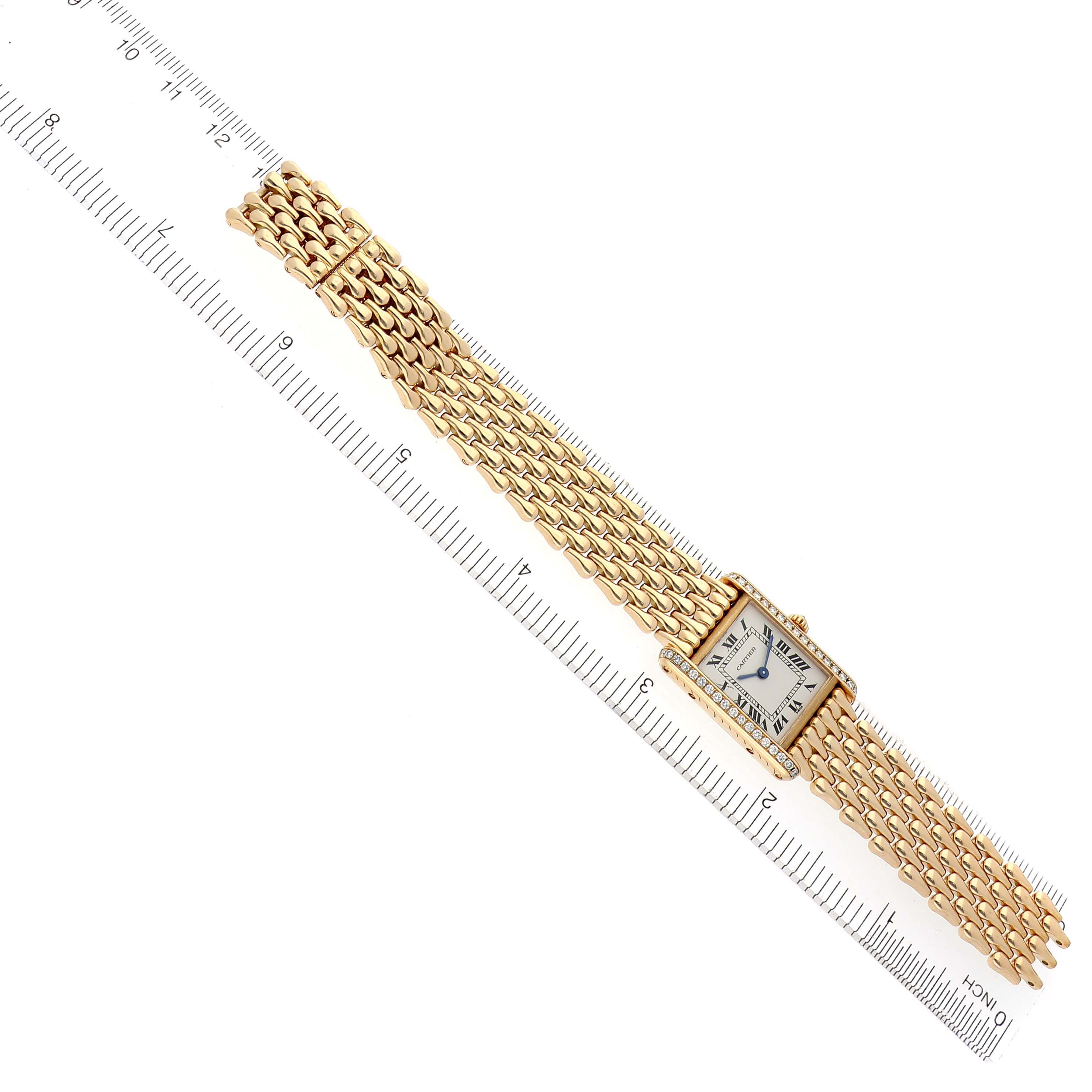The Cartier Tank Louis WA2013K3 Women's Yellow Gold Silver Dial WA2013K3 Women's Yellow Gold Silver Dial watch is shown from a top-down angle, displaying the face, bracelet, and a ruler for scale.