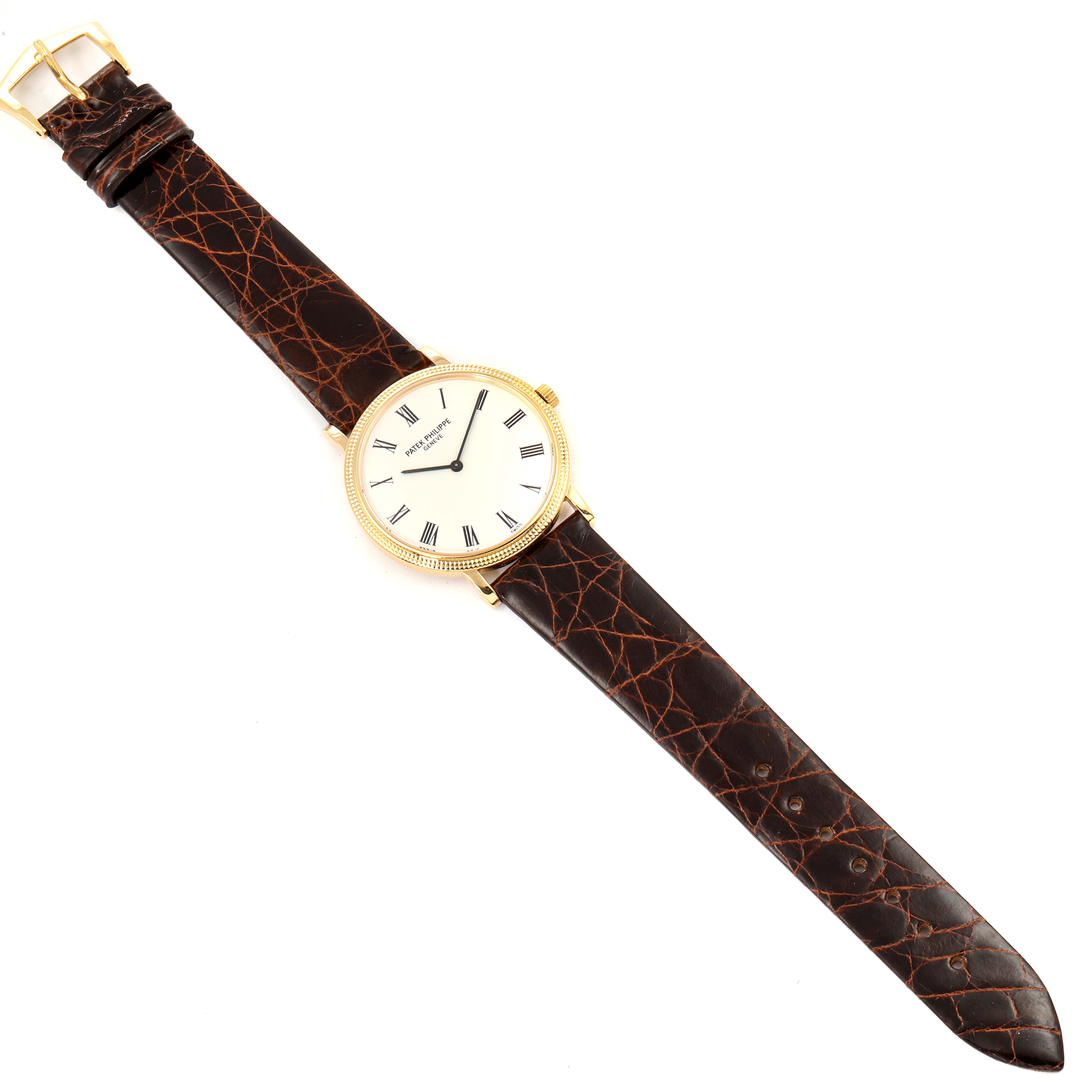 The Patek Philippe Calatrava 5120J Men's Yellow Gold White Dial 5120J Men's Yellow Gold White Dial watch is shown from a top-down angle, displaying the entire watch including its dial, case, and leather strap.