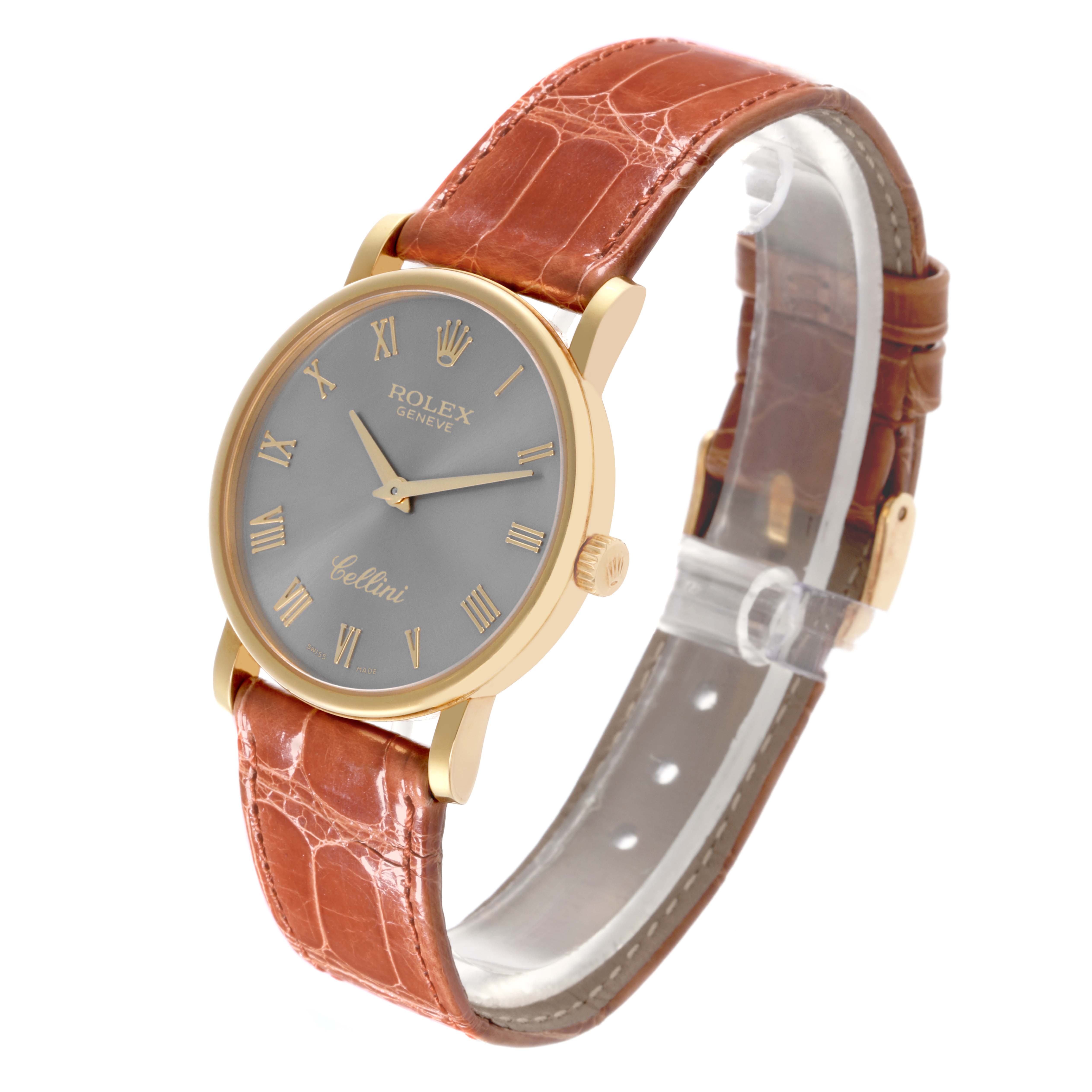 The Rolex Cellini 5115 Men's Yellow Gold Grey Dial 5115 Men's Yellow Gold Grey Dial watch is shown from a three-quarter angle, highlighting its brown leather strap, gold case, and silver dial.