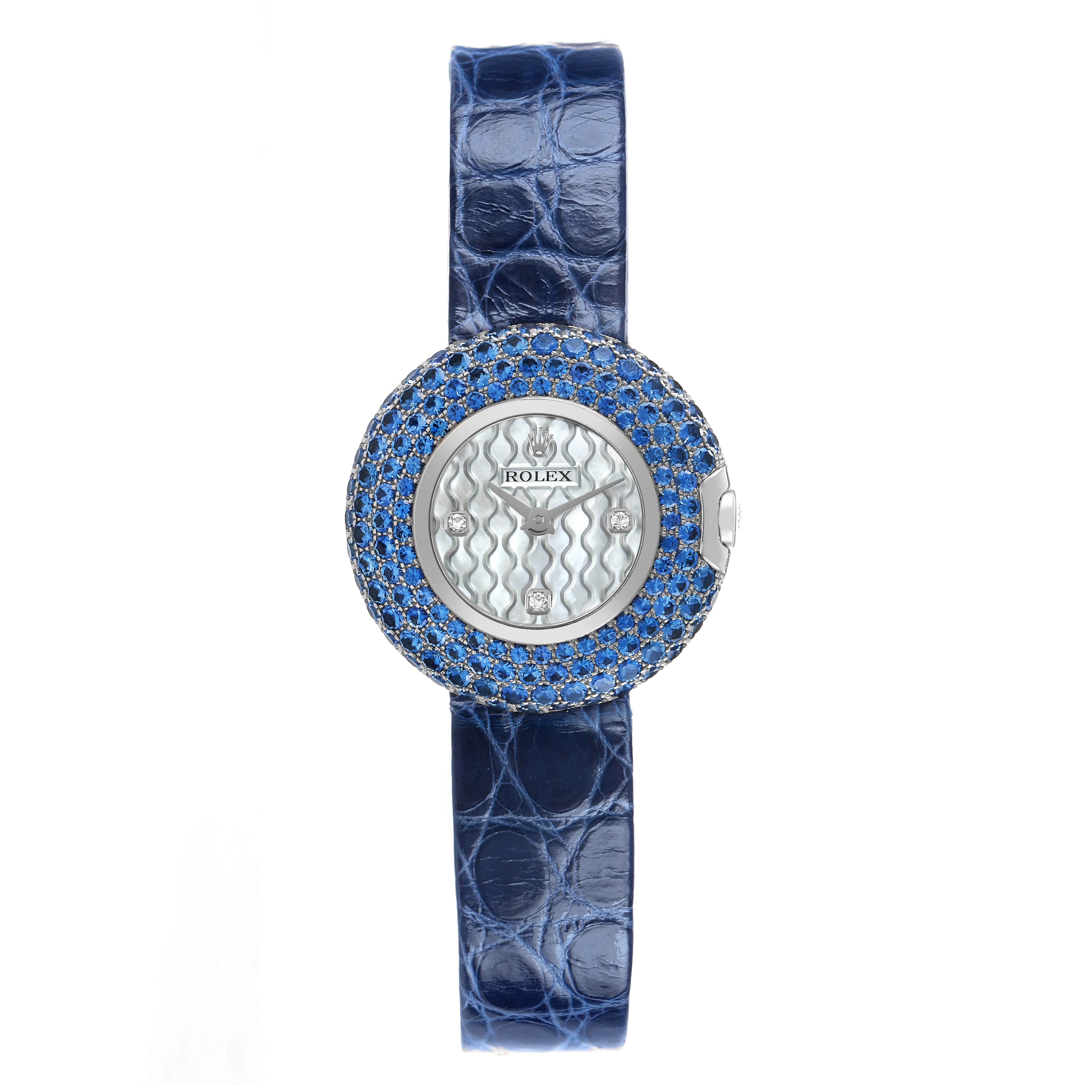 The Rolex Cellini 6201 Women's White Gold Mother of Pearl Dial watch is shown from a top-down view, displaying its blue strap and bejeweled bezel.