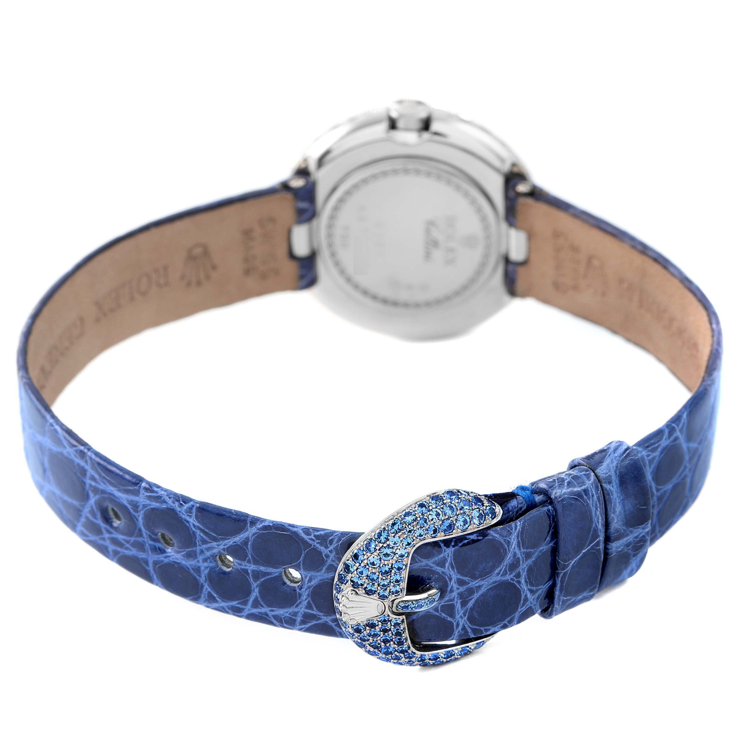 The image shows the back of a Rolex Cellini 6201 Women's White Gold Mother of Pearl Dial watch with an open blue leather strap and a jeweled buckle.