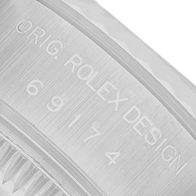 The image shows an angled view of the Rolex Datejust 69174 Women's Stainless Steel White Dial's engraved case, featuring the "ORIG. ROLEX DESIGN" inscription and part number.