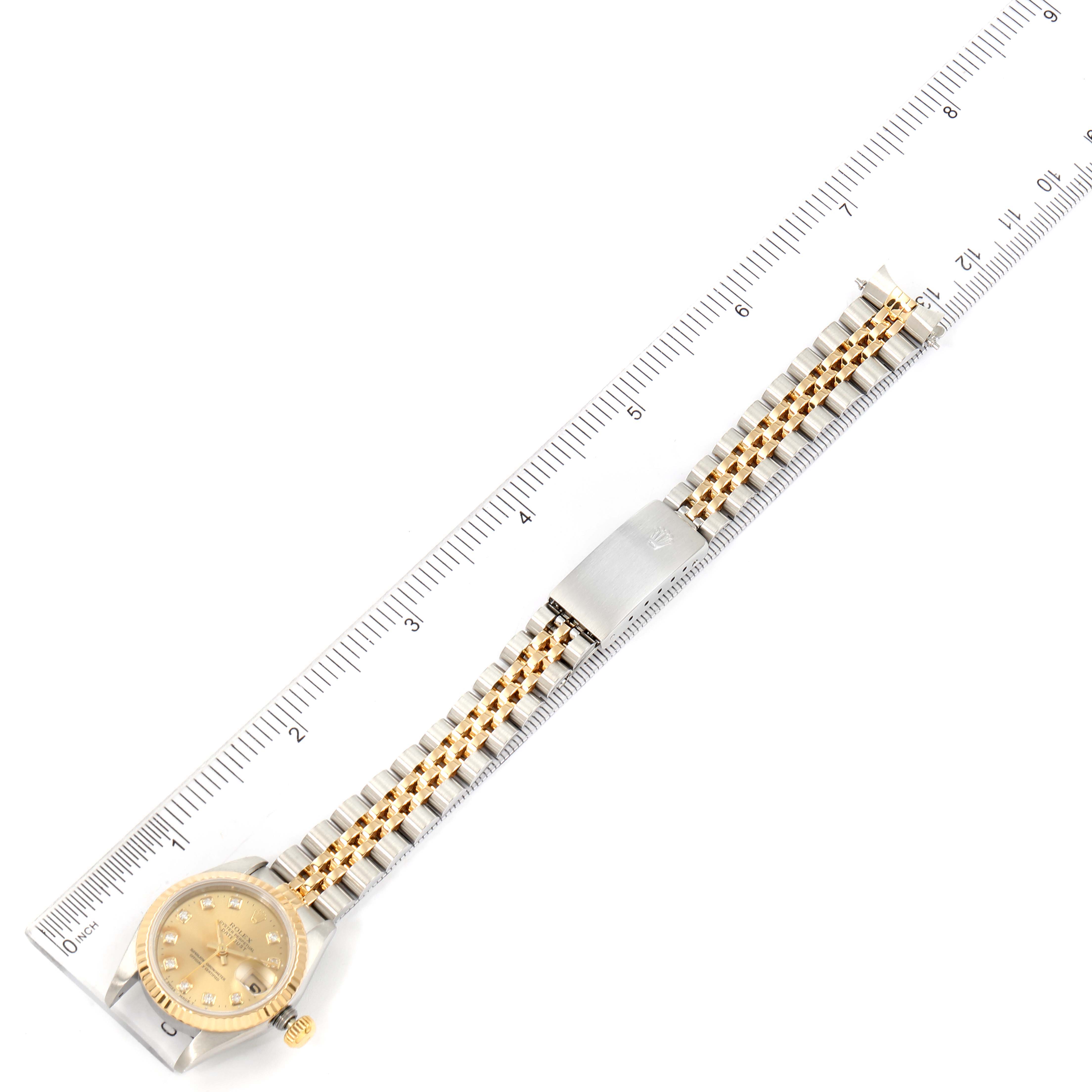 This image shows a top-down view of a Rolex Datejust 69173 Women's Steel and Gold (two tone) Champagne Dial 69173 Women's Steel and Gold (two tone) Champagne Dial watch, including its gold and silver bracelet, placed alongside a ruler.