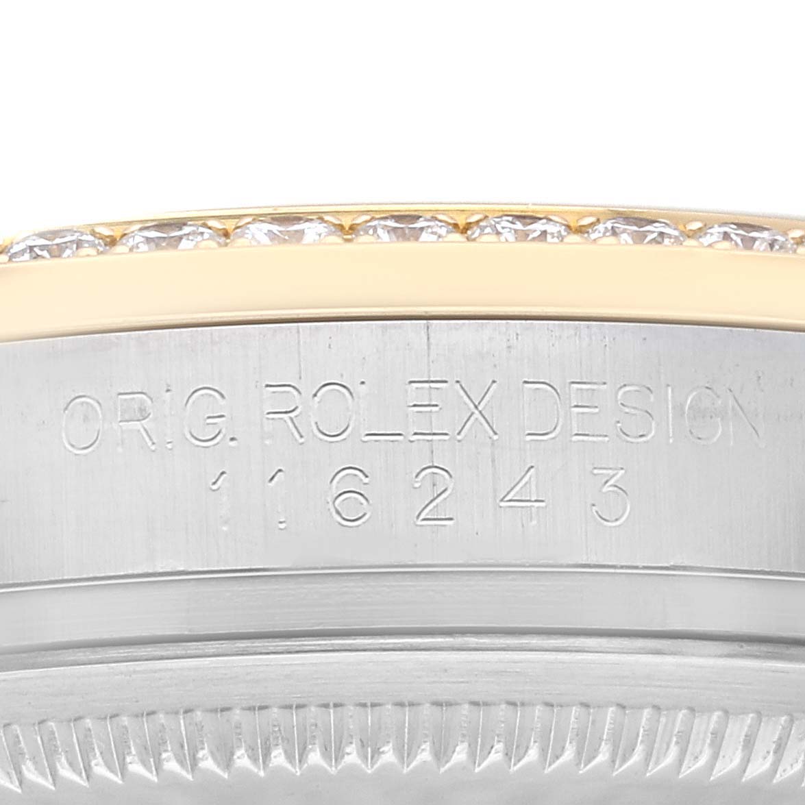 This image shows a close-up of the engraving on the side of a Rolex Datejust 116243 Men's Steel and Gold (two tone) Champagne Dial 116243 Men's Steel and Gold (two tone) Champagne Dial watch case, including part of the bezel with diamonds.