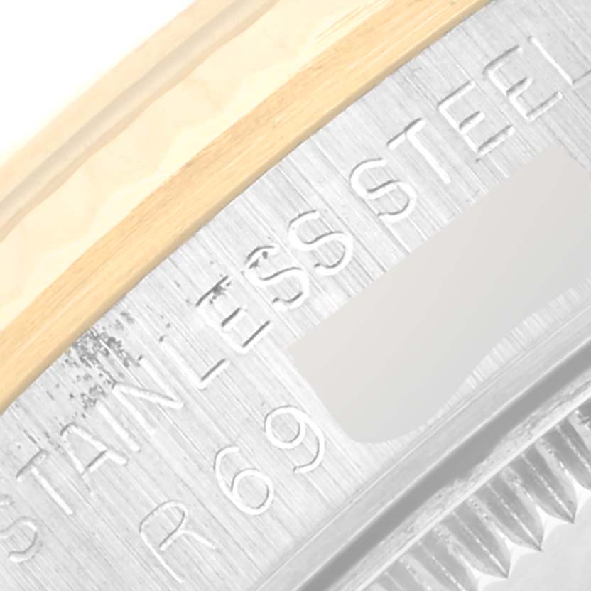 This close-up image shows the edge of a Rolex Mid-Size 68273G Women's Steel and Gold (two tone) Champagne Dial 68273G Women's Steel and Gold (two tone) Champagne Dial watch case featuring engraved text and a part of the bezel.