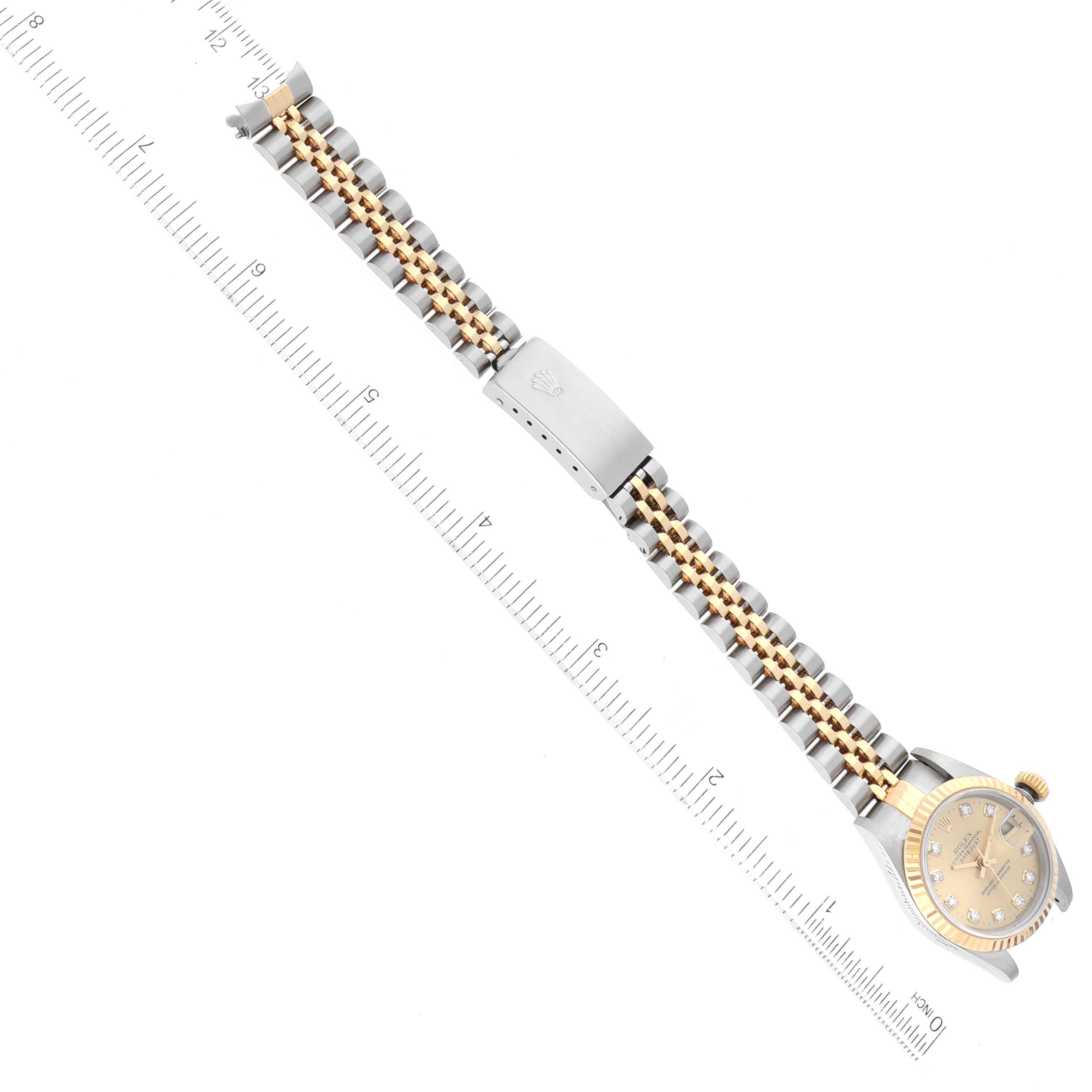 The image shows a Rolex Datejust 79173G Women's Steel and Gold (two tone) Champagne Dial 79173G Women's Steel and Gold (two tone) Champagne Dial watch horizontally with its dial, bezel, and jubilee bracelet alongside a ruler for scale.