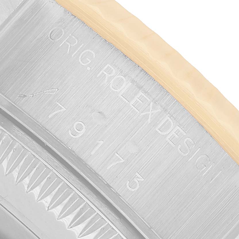 The image shows a close-up of the Rolex Datejust 79173 Women's Steel and Gold (two tone) Silver Dial model's case side with engraved branding and design numbers.