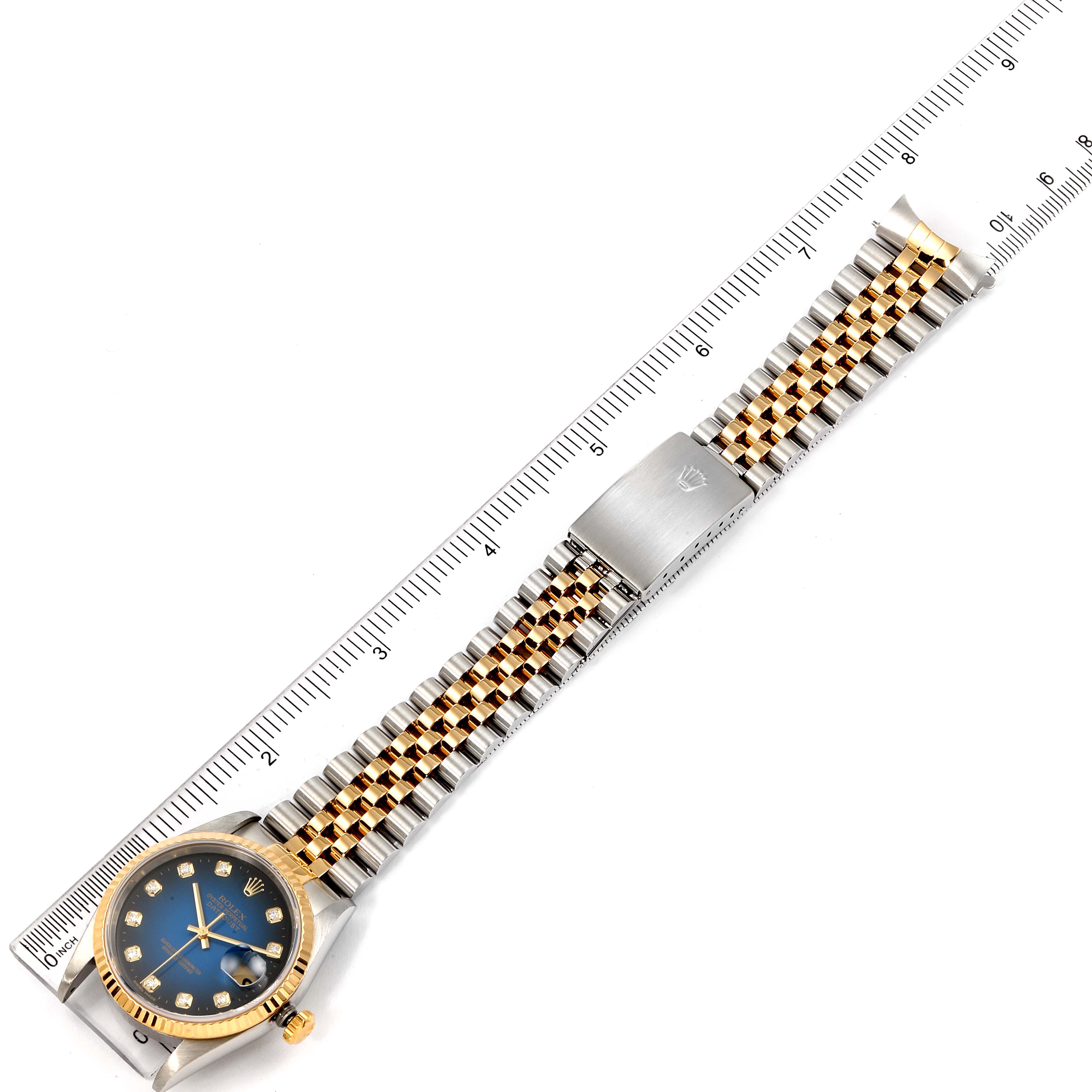 The Rolex Datejust 16233 Men's Steel and Gold (two tone) Blue Dial 16233 Men's Steel and Gold (two tone) Blue Dial watch is shown from a top-down angle, displaying the blue dial, two-tone bracelet, and clasp alongside a ruler for scale.