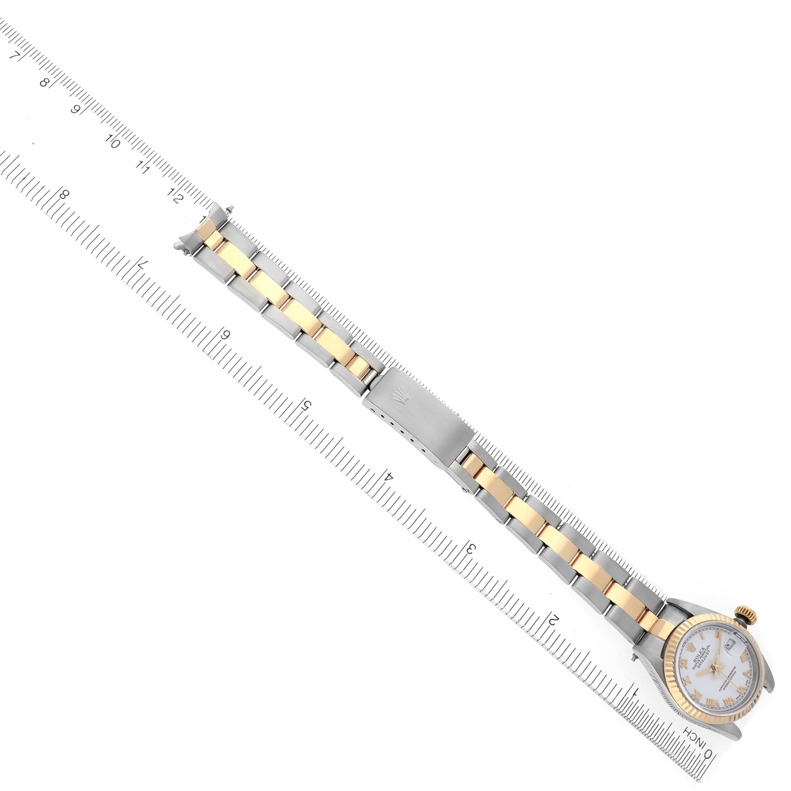 The Rolex Datejust 69173 Women's Steel and Gold (two tone) White Dial 69173 Women's Steel and Gold (two tone) White Dial watch is shown from a top view, highlighting the dial, bezel, and two-tone bracelet with a clasp, alongside a ruler.