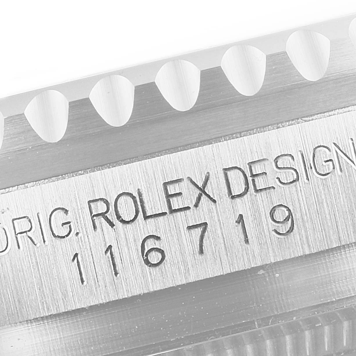 The image shows a close-up of the side engraving and part of the fluted bezel of a Rolex GMT-Master 116719 Men's White Gold Black Dial 116719 Men's White Gold Black Dial watch.