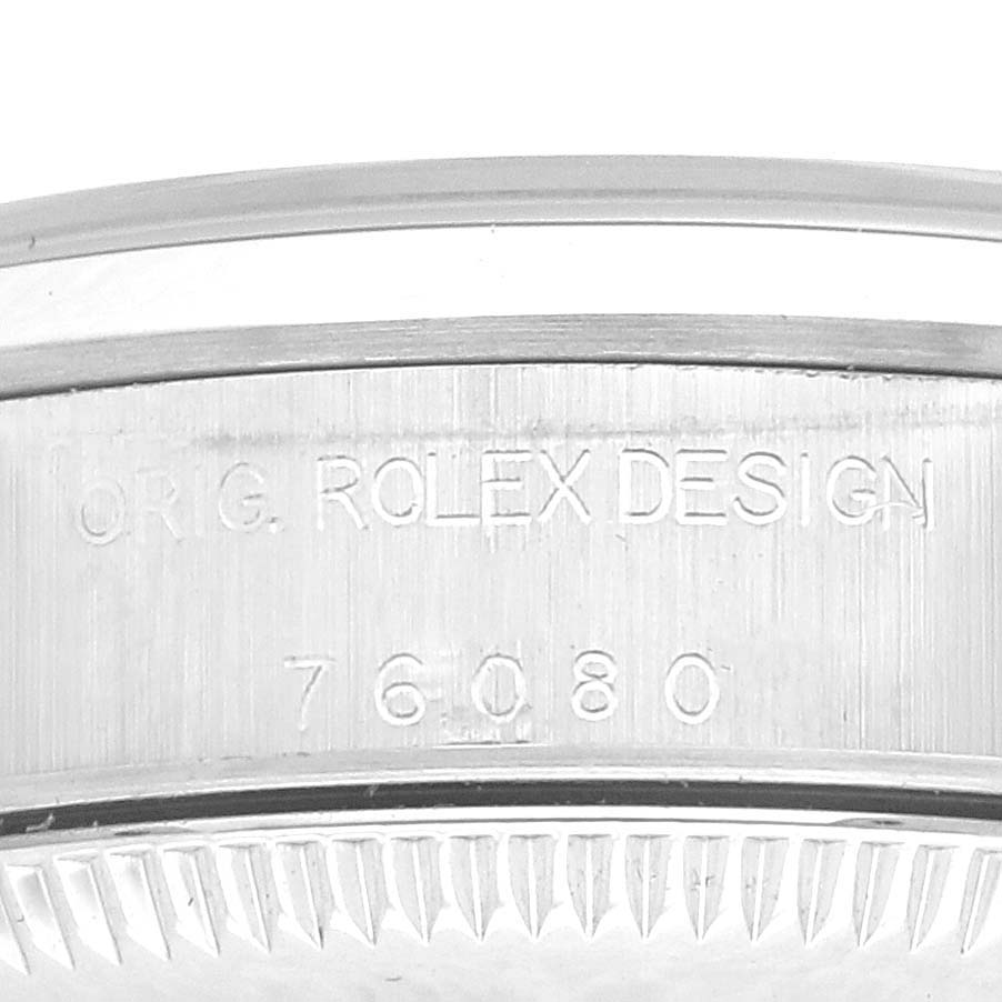 The image shows a close-up of the side of a Rolex Oyster Perpetual 76080 Women's Stainless Steel Black Dial 76080 Women's Stainless Steel Black Dial watch case with engraved text and design number.