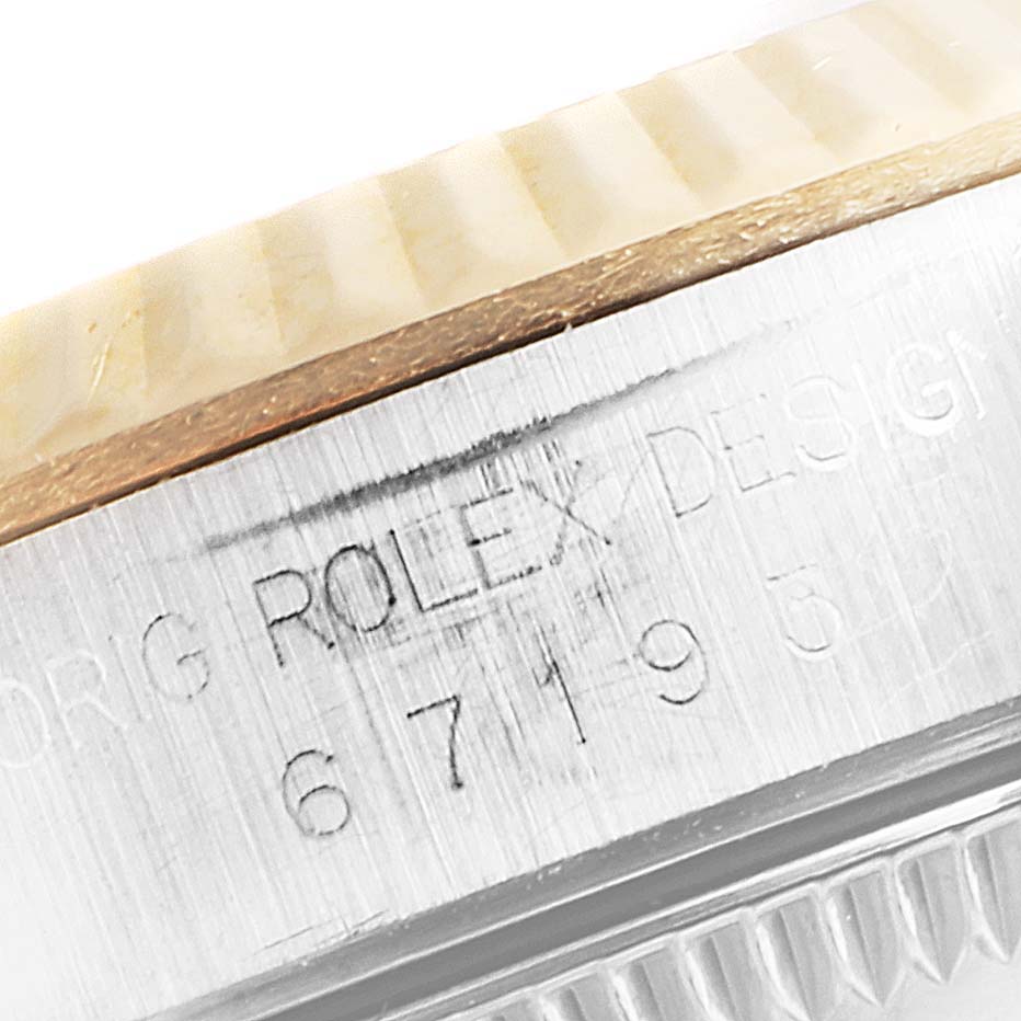 The image shows a close-up of the side of the Rolex Oyster Perpetual 67193 Women's Steel and Gold (two tone) White Dial 67193 Women's Steel and Gold (two tone) White Dial watch, focusing on the engraved model number and part of the fluted bezel.