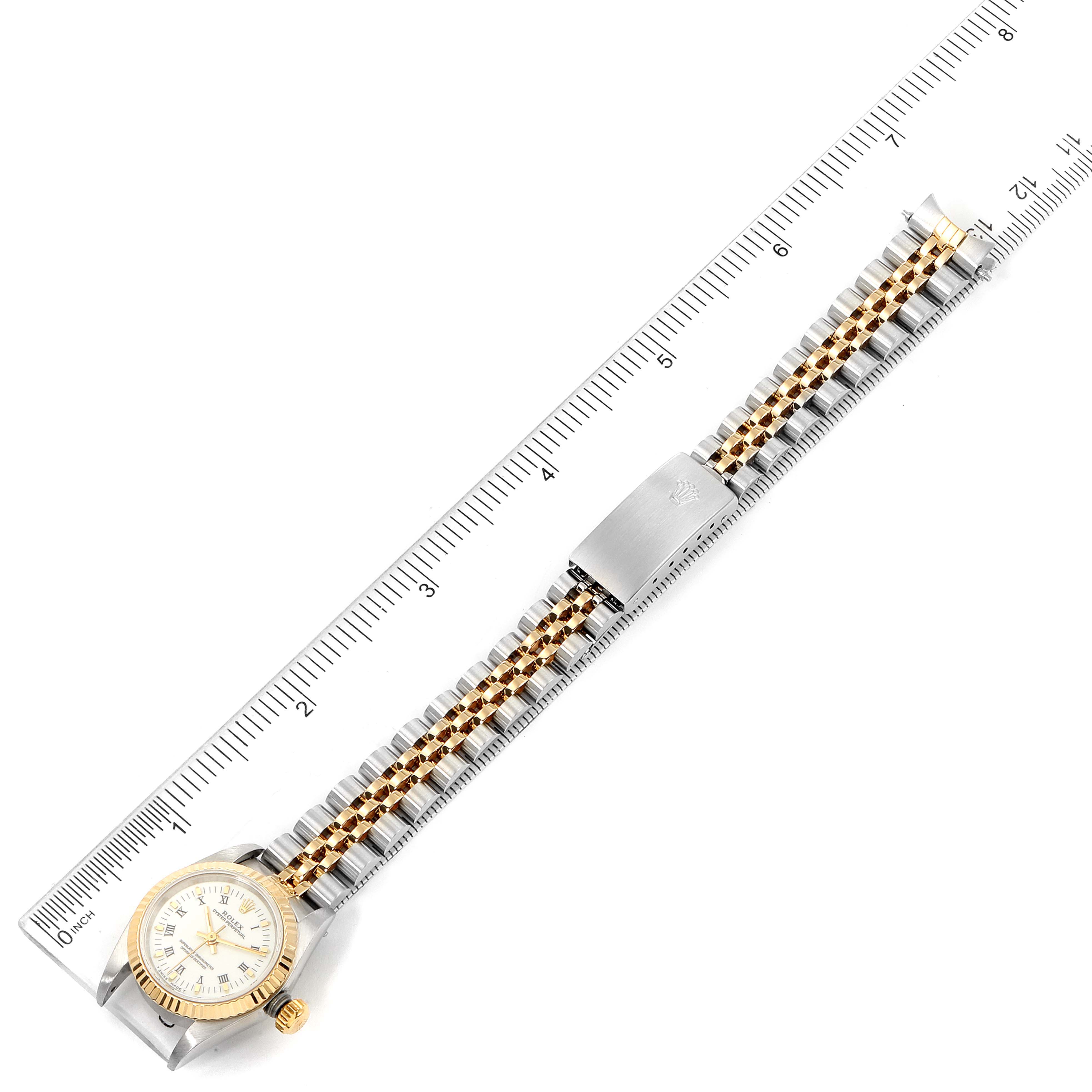 This image shows the entire length of a Rolex Oyster Perpetual 67193 Women's Steel and Gold (two tone) White Dial 67193 Women's Steel and Gold (two tone) White Dial watch, including the face and bracelet, positioned alongside a ruler.