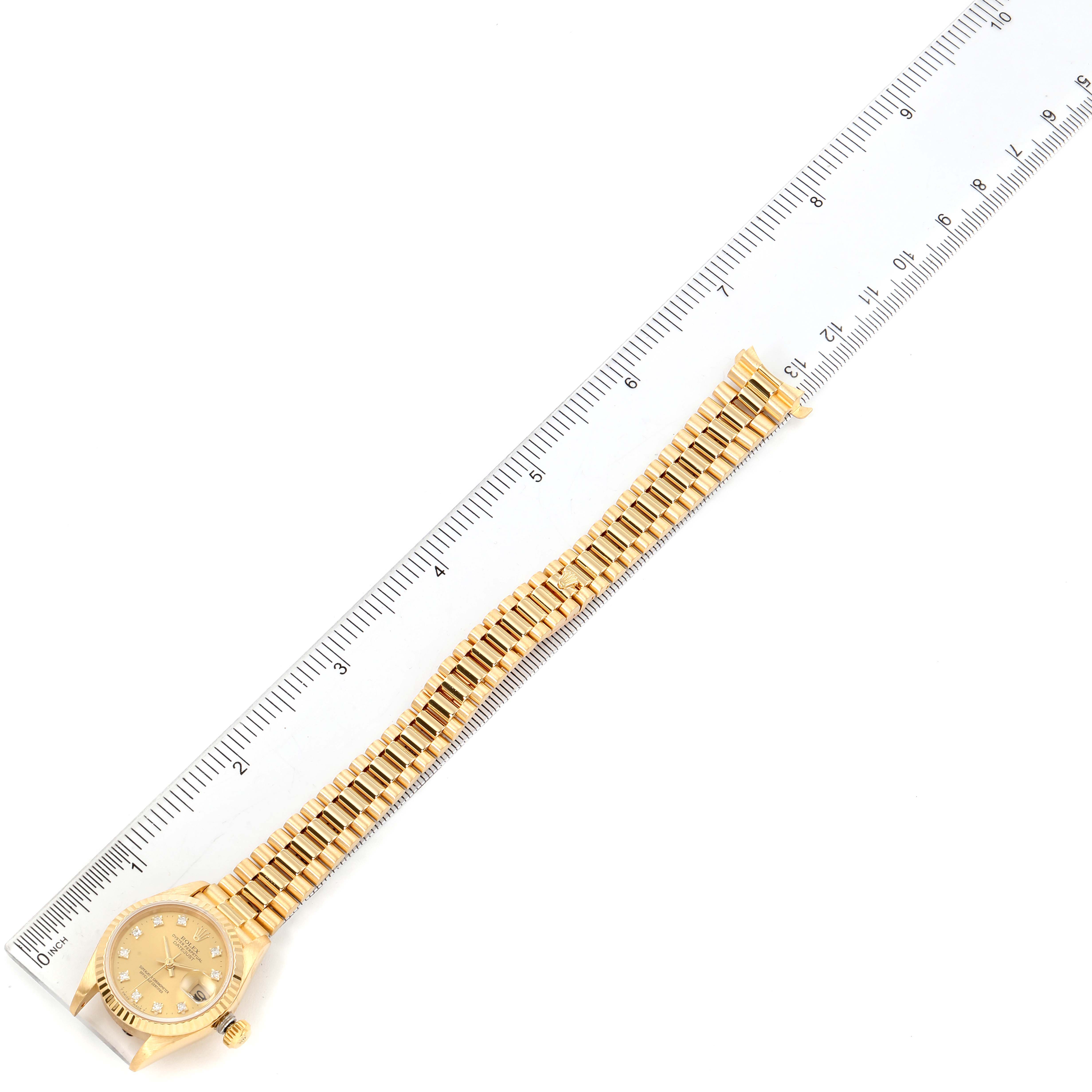 The Rolex President 69178 Women
s Yellow Gold Champagne Dial 69178 Women
s Yellow Gold Champagne Dial model watch is shown flat with the entire length of the band aligned next to a ruler for measurement.