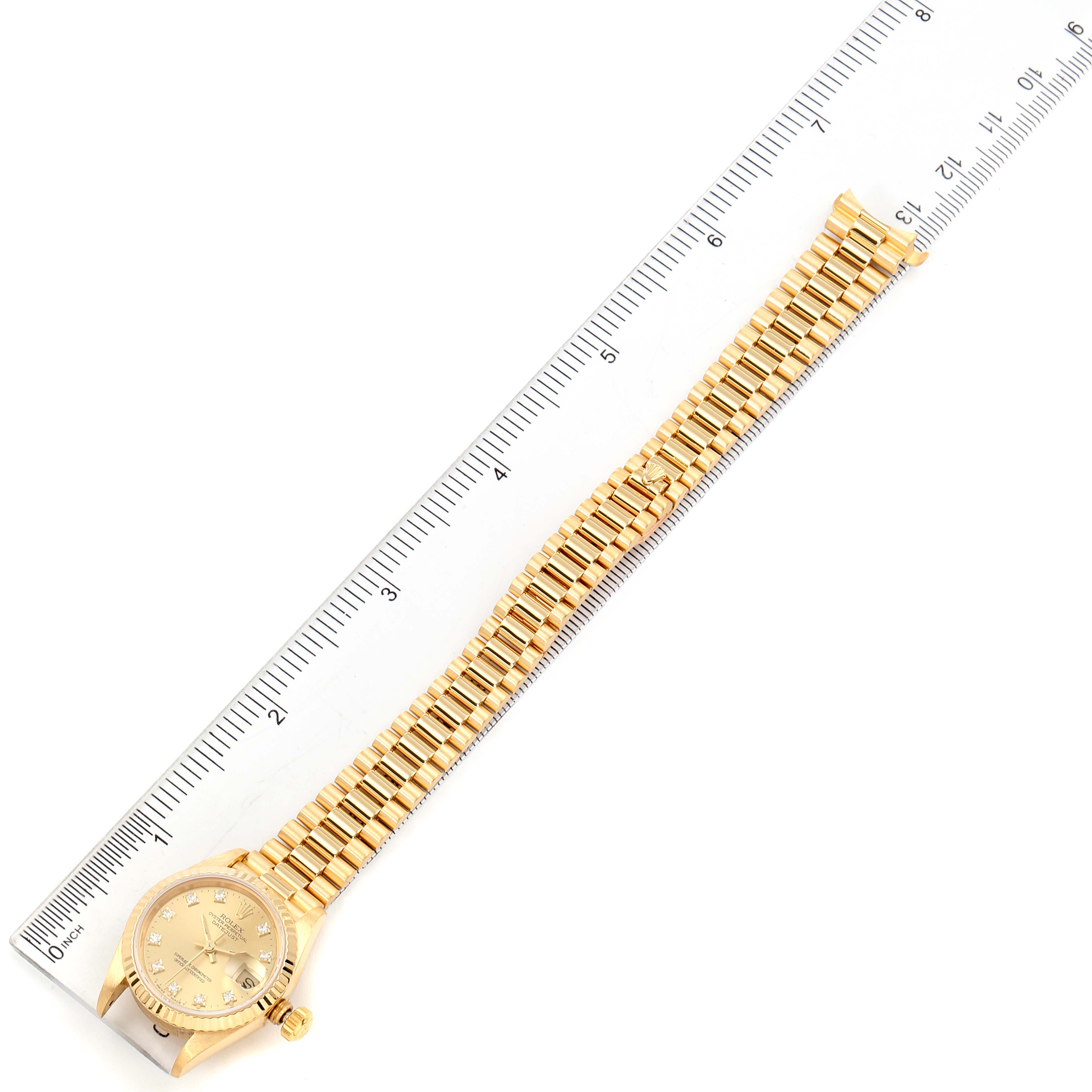 The Rolex President 69178 Women
s Yellow Gold Champagne Dial 69178 Women
s Yellow Gold Champagne Dial model watch is shown from a top-down angle, displaying the face and the full length of the band next to a ruler.