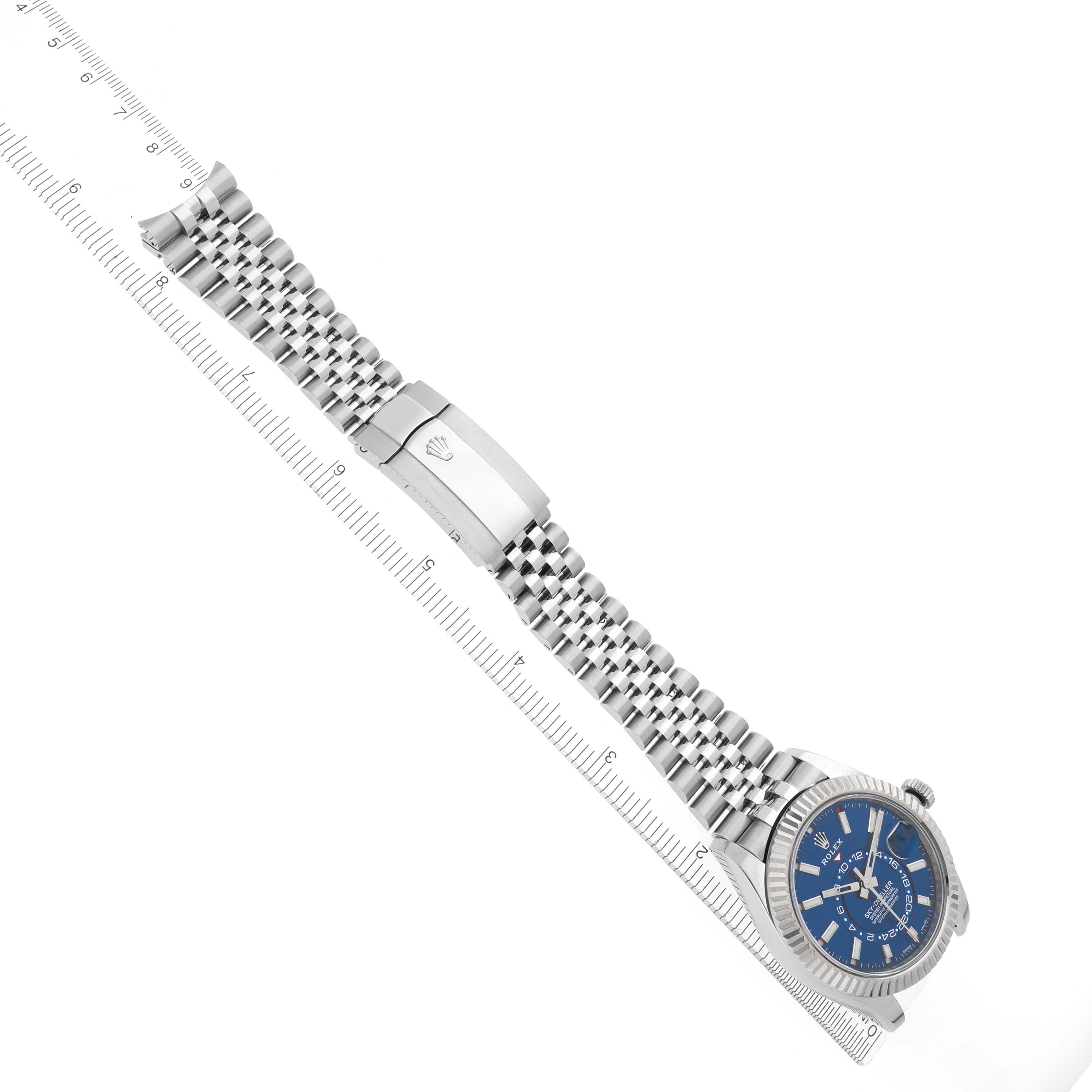 The Rolex Sky-Dweller 326934 Men's Stainless Steel Blue Dial 326934 Men's Stainless Steel Blue Dial watch is shown from an angled view, highlighting its blue dial and metal bracelet alongside a ruler.