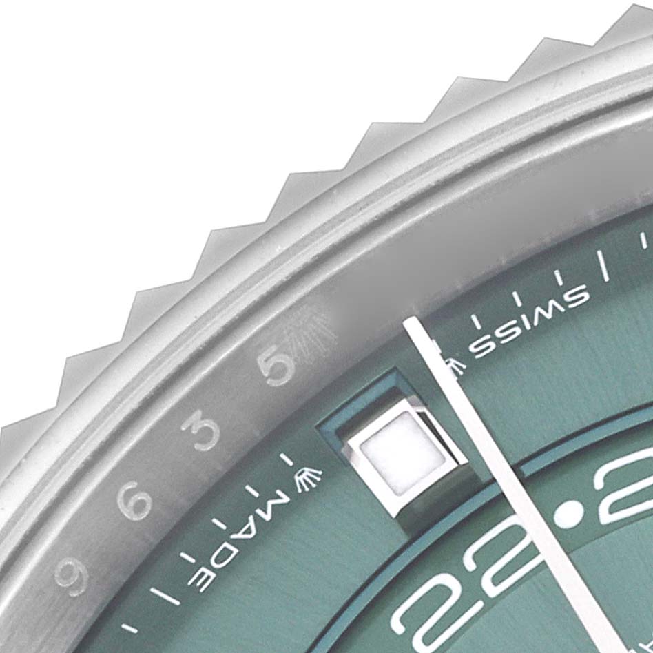 The image shows a close-up of the Rolex Sky-Dweller 336934 Men's Stainless Steel Green Dial 336934 Men's Stainless Steel Green Dial's dial and bezel, highlighting the date display and Swiss marking.