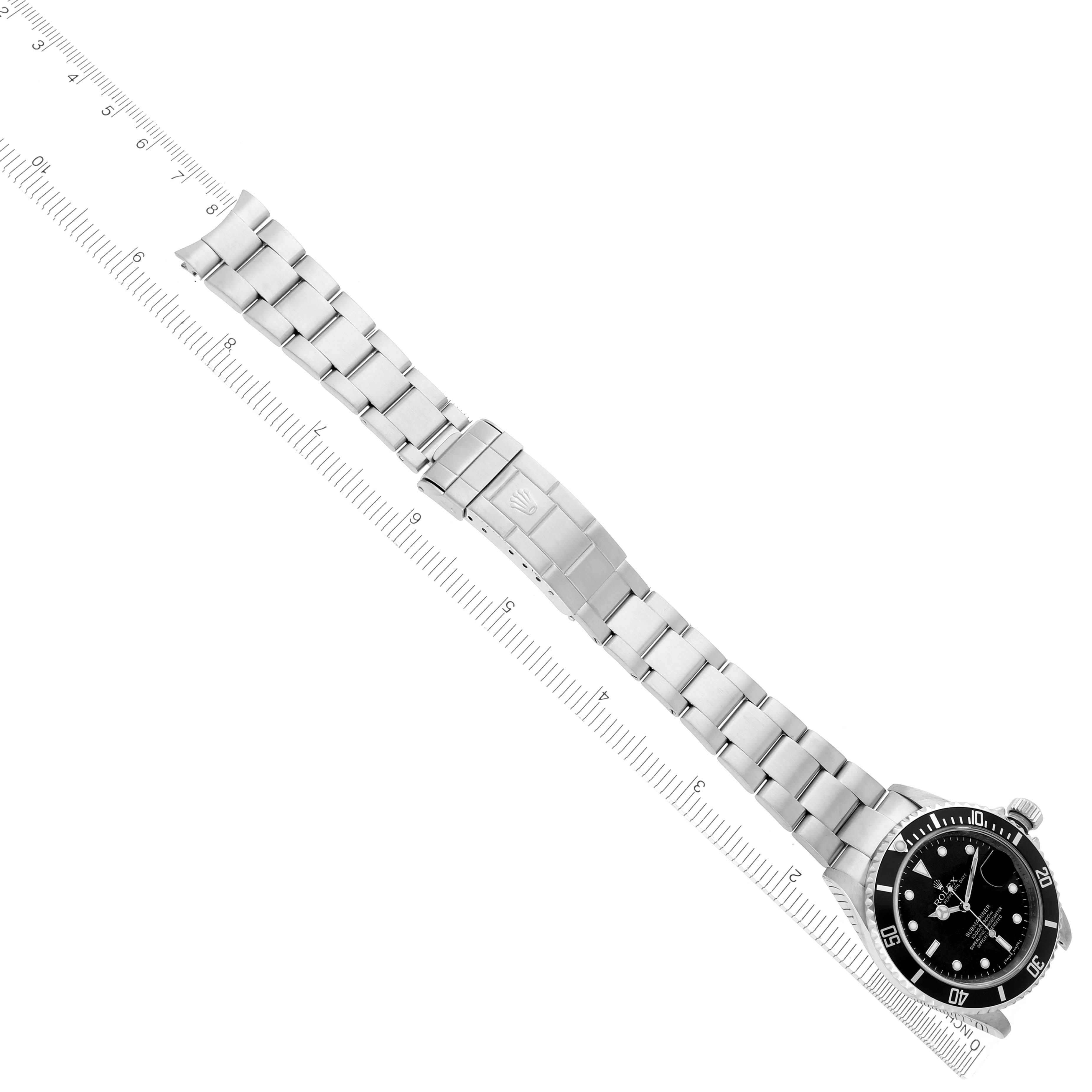 The Rolex Submariner 16610 Men's Stainless Steel Black Dial 16610 Men's Stainless Steel Black Dial is shown laid flat with its full bracelet, alongside a ruler for scale.