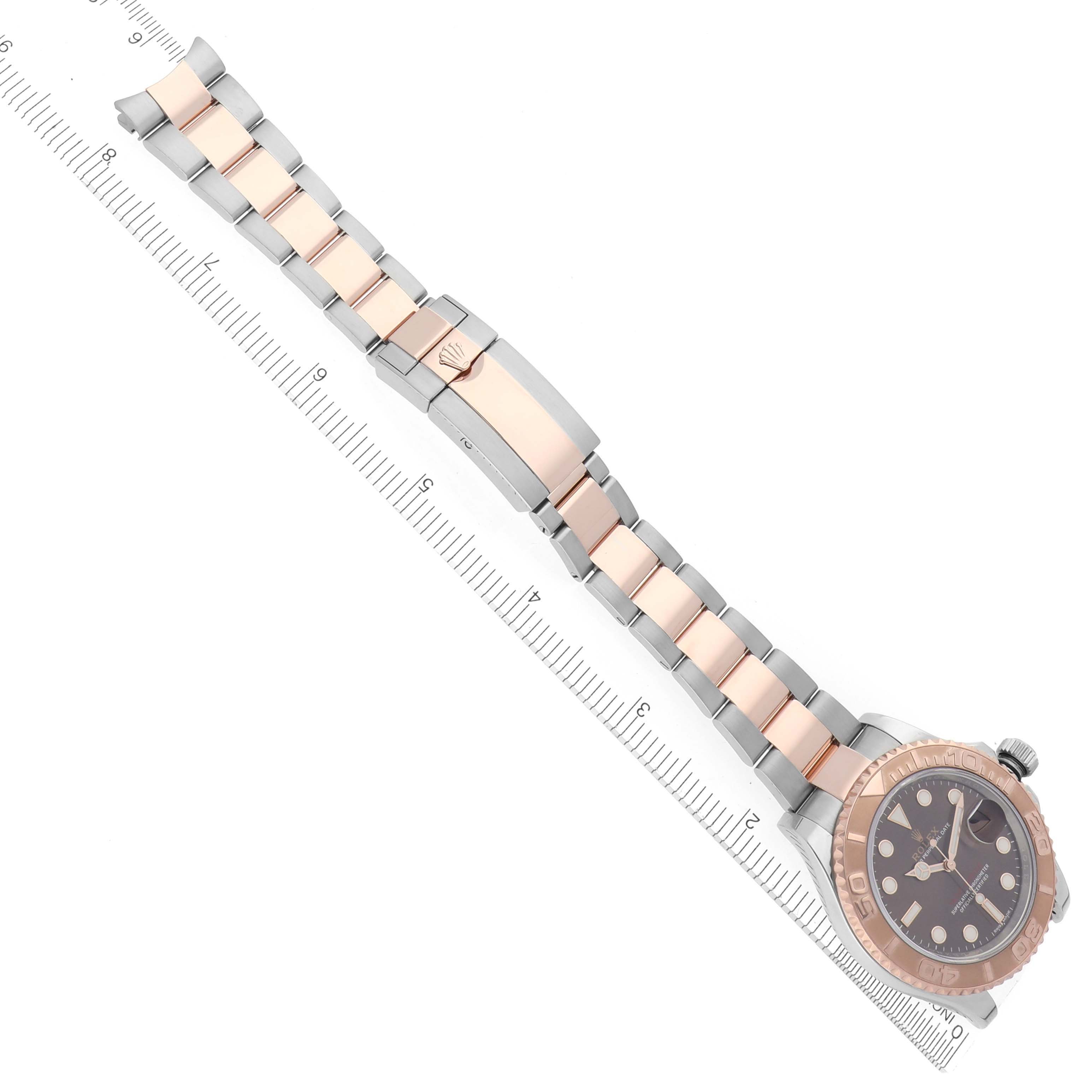 The Rolex Yacht-Master 116621 Men's Steel and Gold (two tone) Brown Dial 116621 Men's Steel and Gold (two tone) Brown Dial watch is shown at an angle displaying the bracelet, clasp, and watch face alongside a ruler.