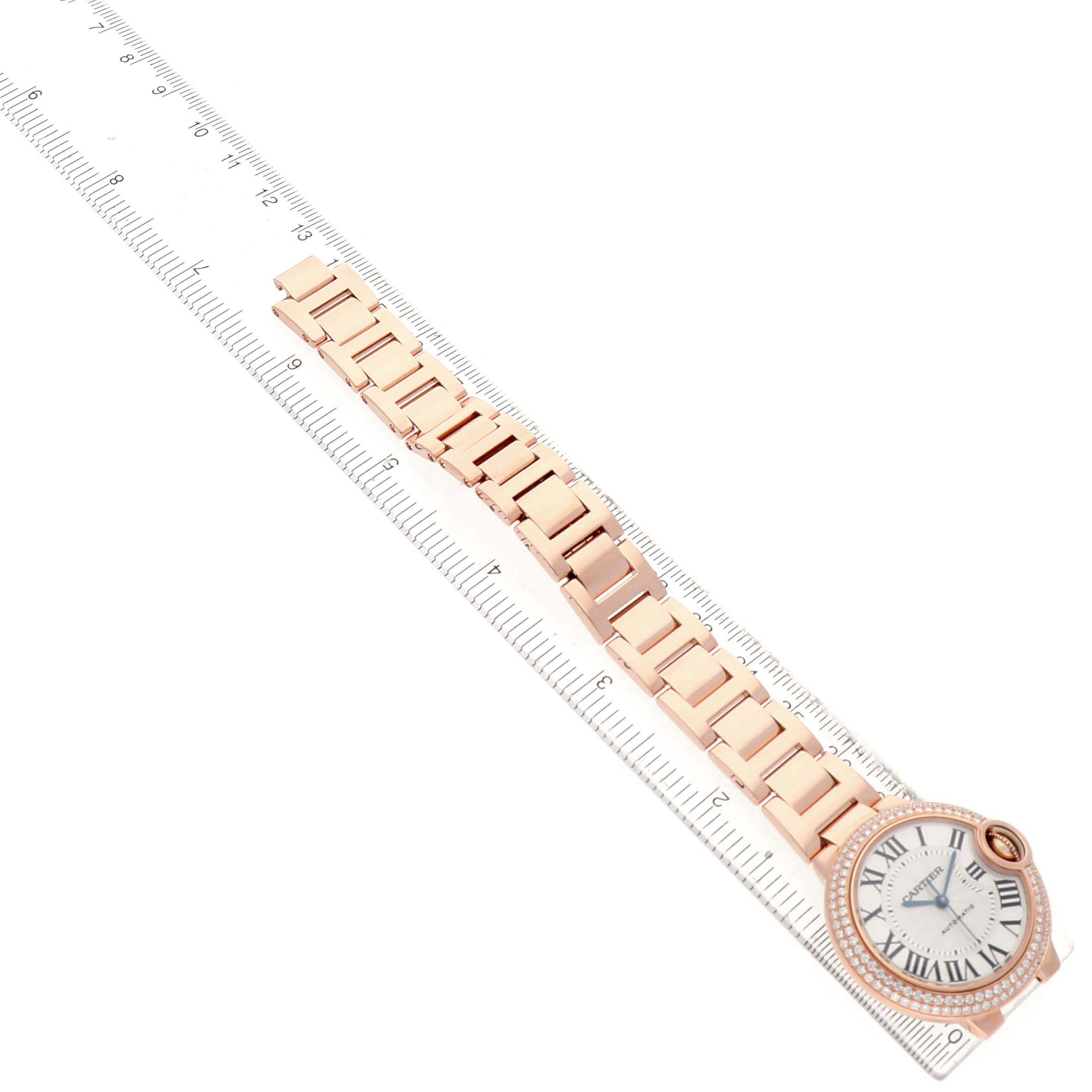 The image shows a top view of the Cartier Ballon Bleu 79017 Women's Rose Gold Silver Dial watch, highlighting its bracelet and face placed alongside a ruler.