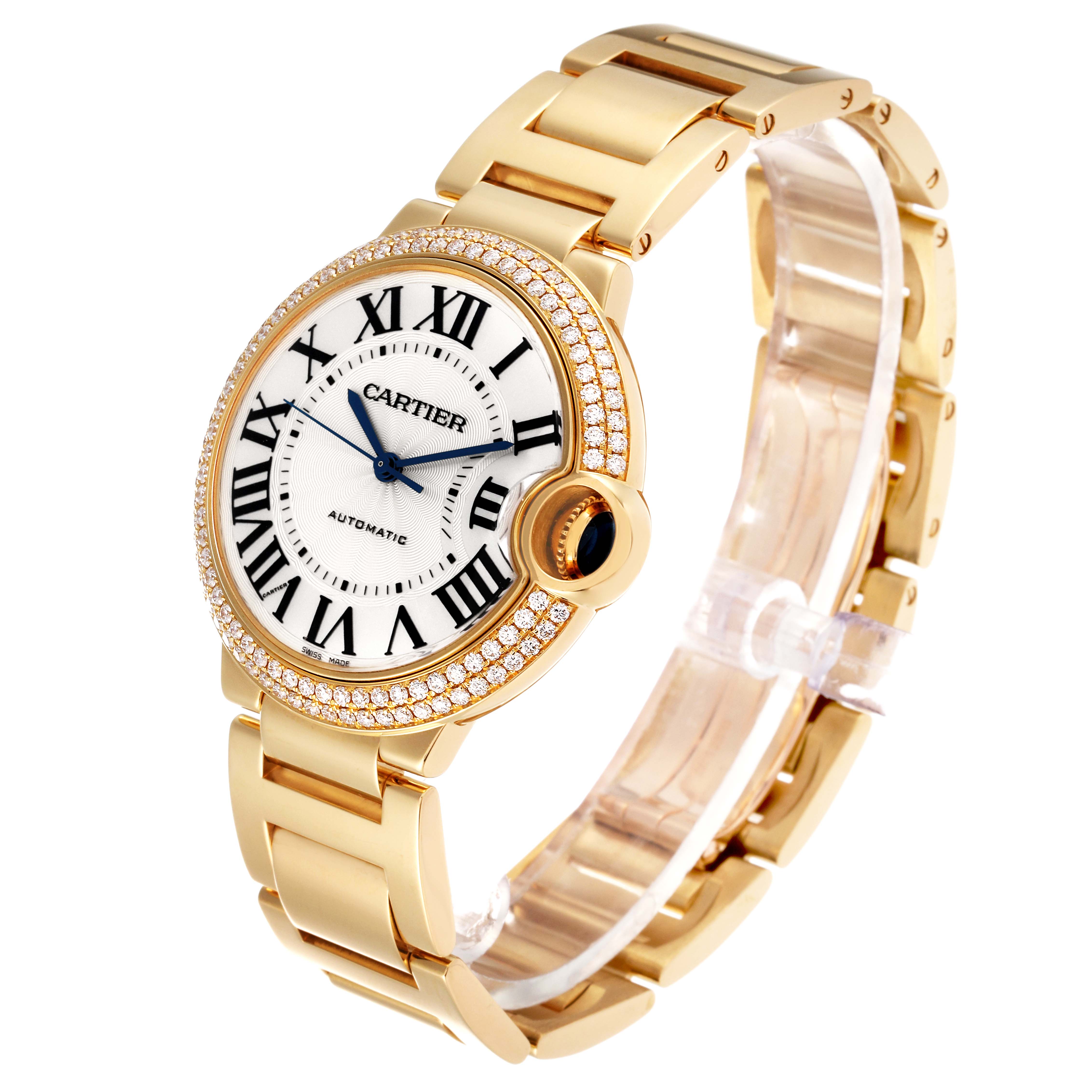 The image shows a Cartier Ballon Bleu WE9004Z3 Women
s Yellow Gold Silver Dial WE9004Z3 Women
s Yellow Gold Silver Dial watch at a three-quarter angle, highlighting its gold bracelet and diamond-studded bezel.