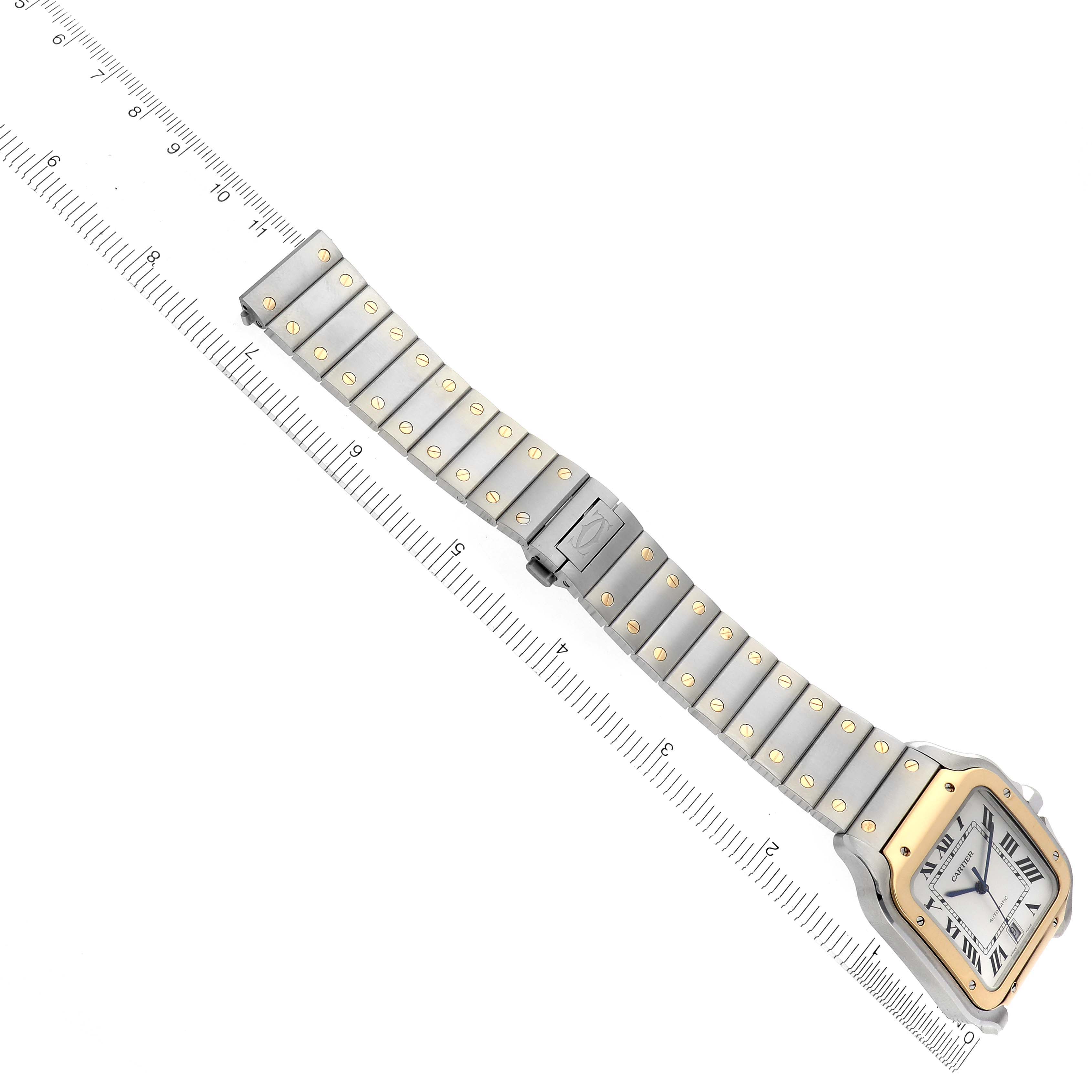 The Cartier Santos W2SA0009 Men's Steel and Gold (two tone) Silver Dial W2SA0009 Men's Steel and Gold (two tone) Silver Dial watch is shown at an angled view, displaying its face and full metal bracelet alongside a ruler for scale.