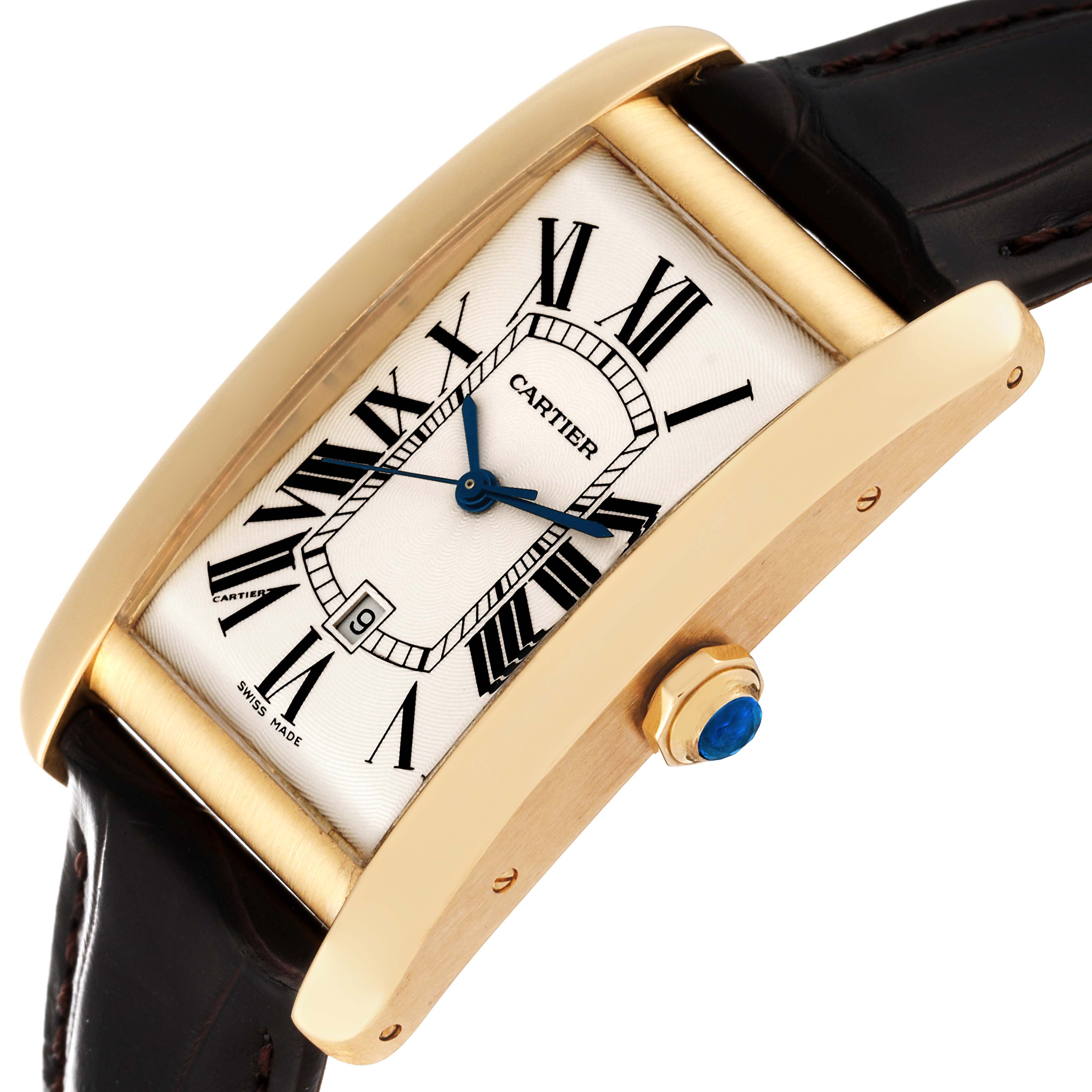 This image shows a Cartier Tank Americaine W2603156 Men
s Yellow Gold Silver Dial W2603156 Men
s Yellow Gold Silver Dial watch at an angle, highlighting its rectangular face, blue hands, roman numeral indices, and gold casing.