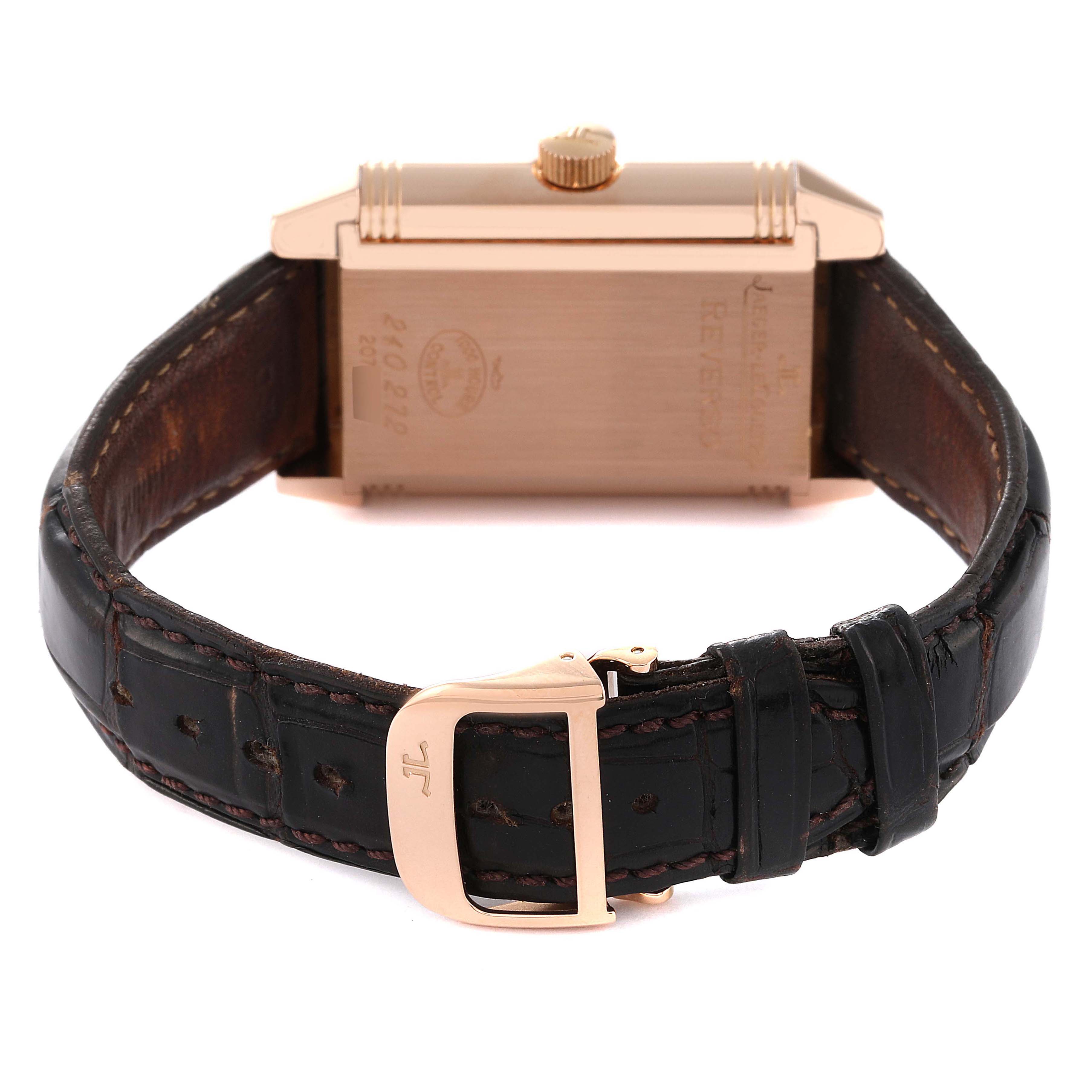 The image shows the back of a Jaeger-LeCoultre Reverso watch, highlighting its case, crown, and leather strap with a branded clasp.