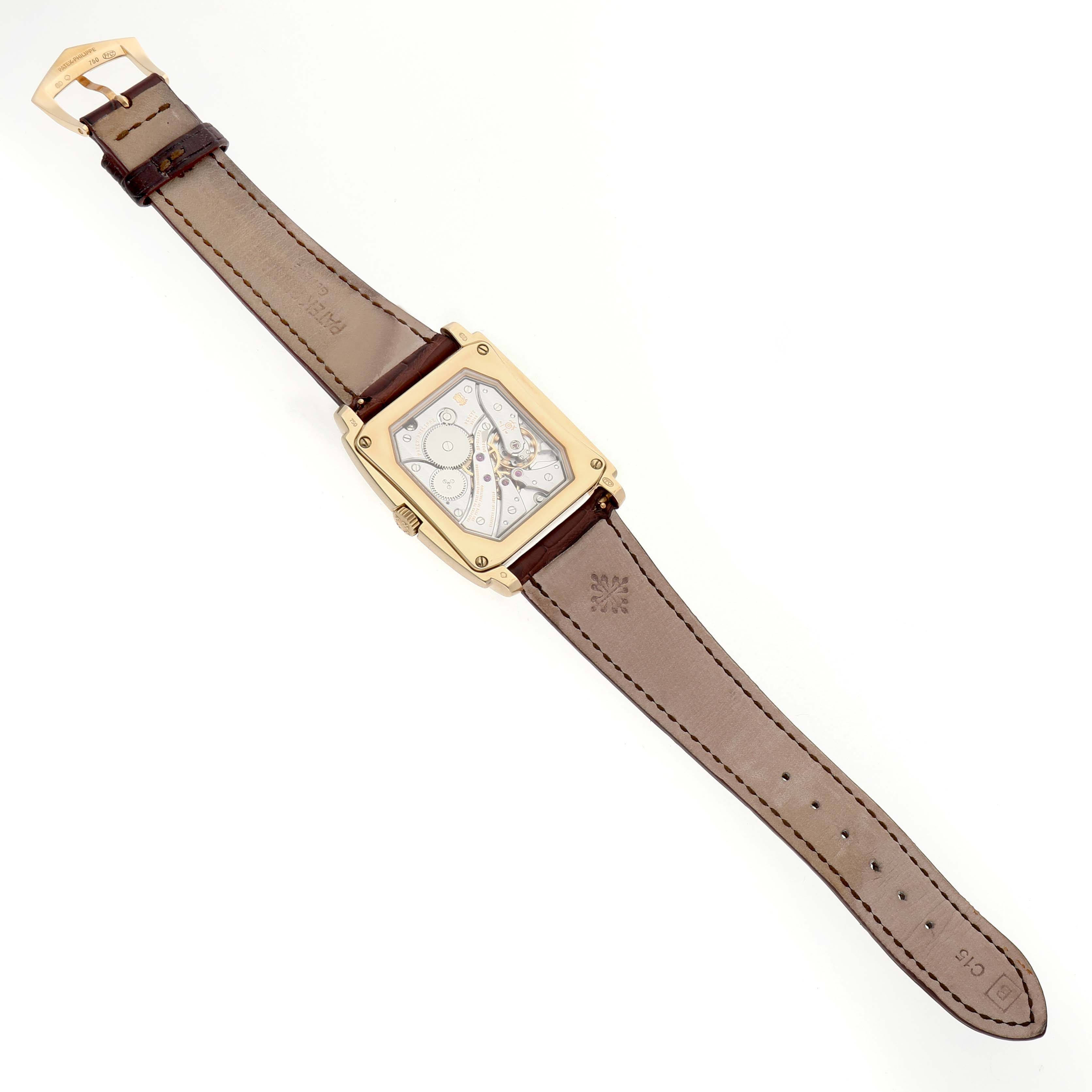 The Patek Philippe Gondolo 5124J-001 Men's Yellow Gold Silver Dial watch is shown from the back, displaying its movement and leather strap with a gold buckle.